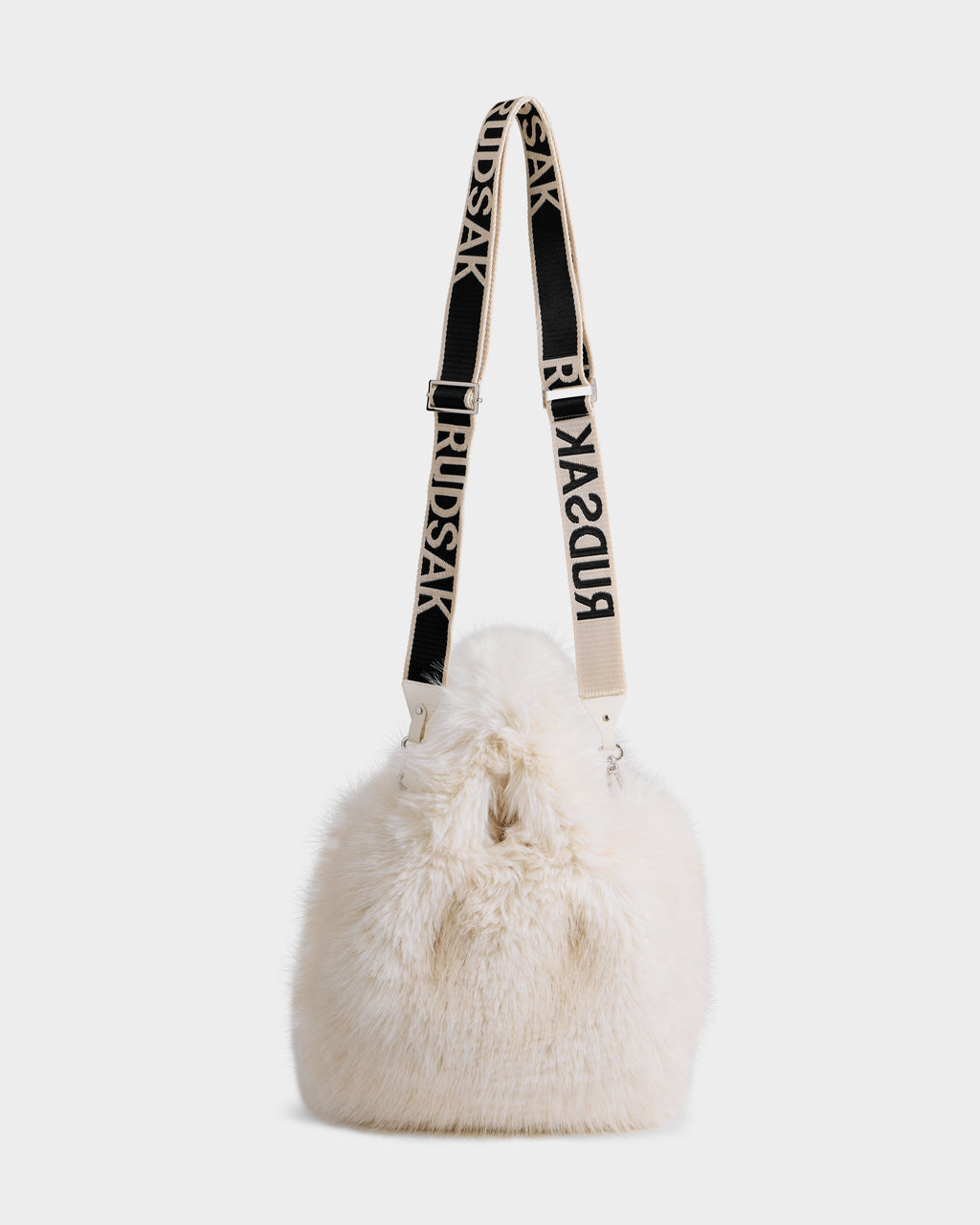 The Rudsak CABAS - 8325545 Vanilla is a white faux fur mini tote with a wide adjustable black strap featuring bold RUDSAK lettering—a chic statement for winter outfits, showcased on a plain white background.