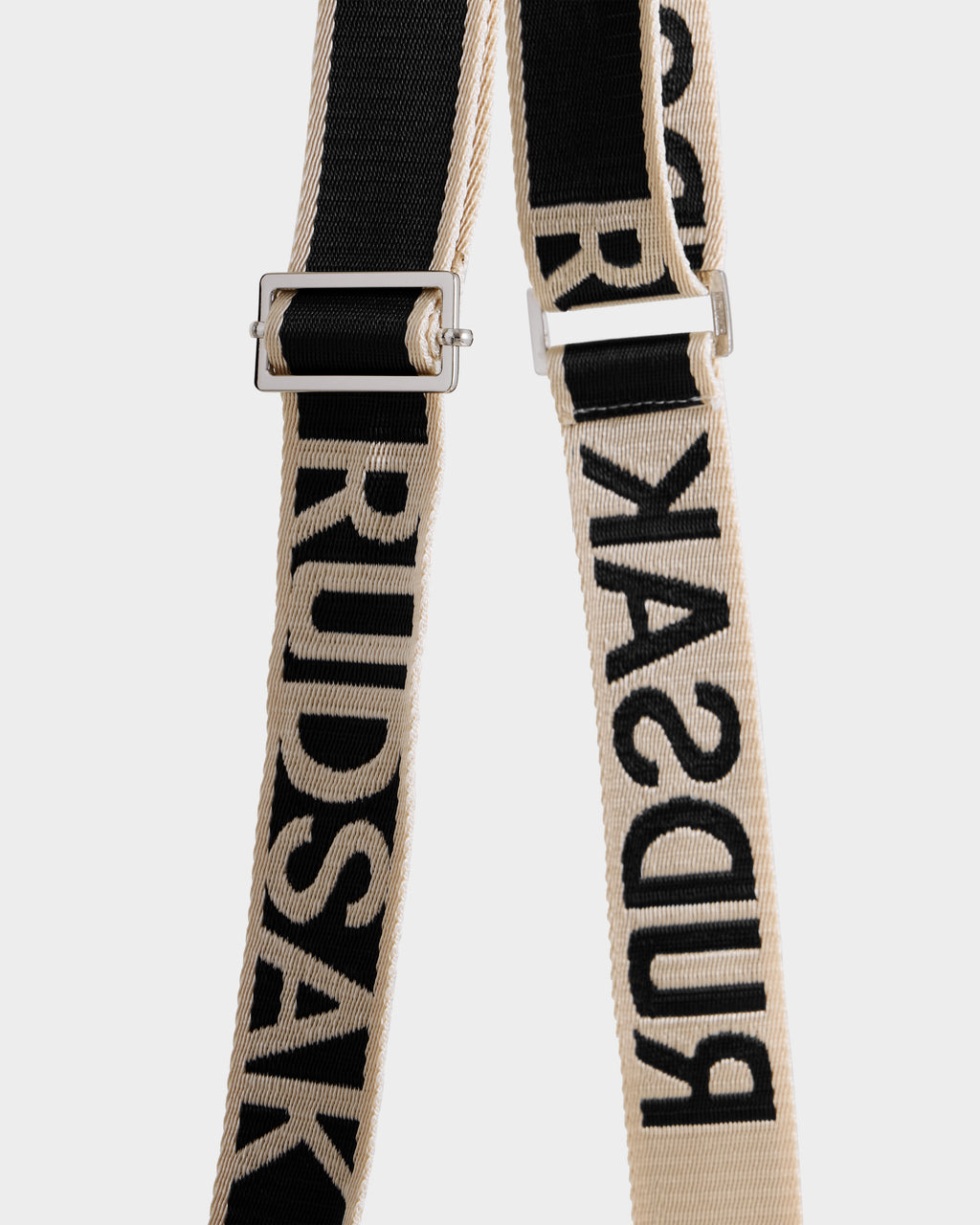 Two adjustable fabric straps, one black and one beige, with bold Rudsak branding and metal hardware. The CABAS - 8325545 Vanilla is a statement accessory—perfect for winter layers or pairing with a faux fur mini tote.