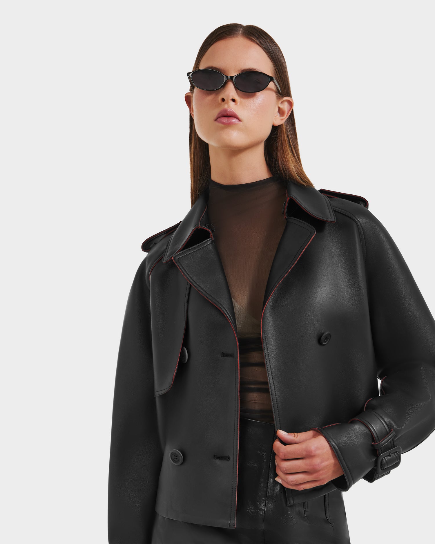 A woman stands confidently against a plain white background wearing the Rudsak CASSIE S-B - 8125554 Black bonded leather jacket.