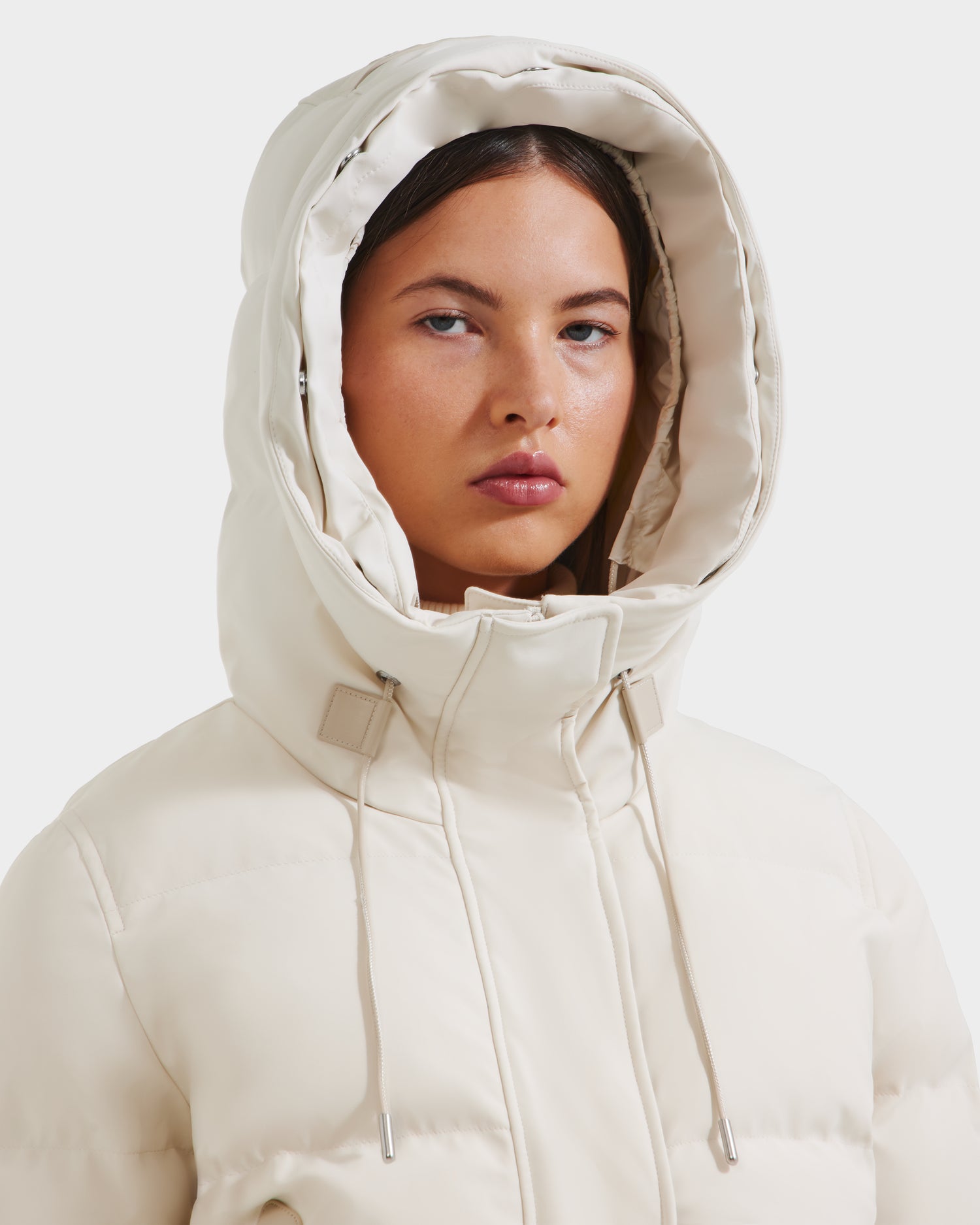 A woman wears the Rudsak CIEYNA - 8125579 Vanilla weather-resistant bomber jacket with a hood, posing against a plain white background.