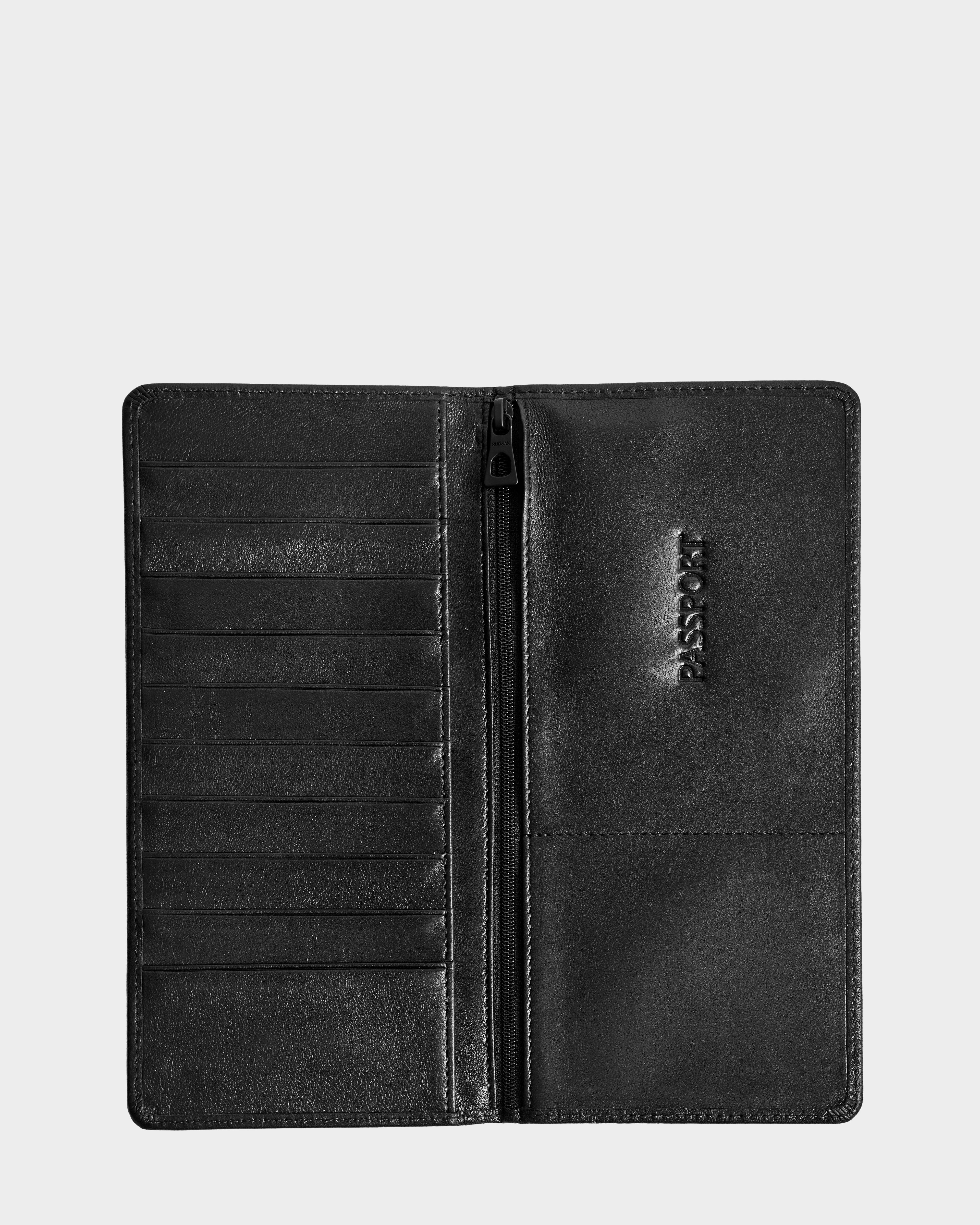 The CLEO - 9425522 Black by Rudsak is a sleek unisex black leather passport holder and travel wallet, featuring card slots, a central zip pocket, and an embossed PASSPORT section—perfect for organized journeys.