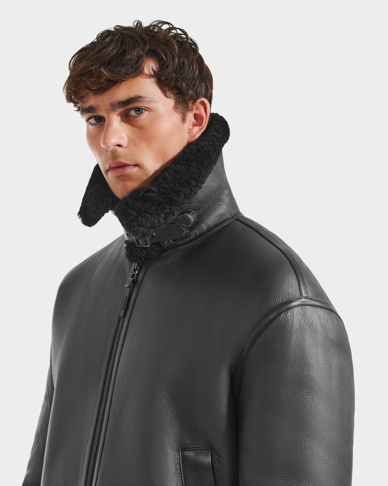 A man wears the Rudsak CONOR - 6124596 Black jacket featuring a shearling collar—a stylish choice for any winter wardrobe.