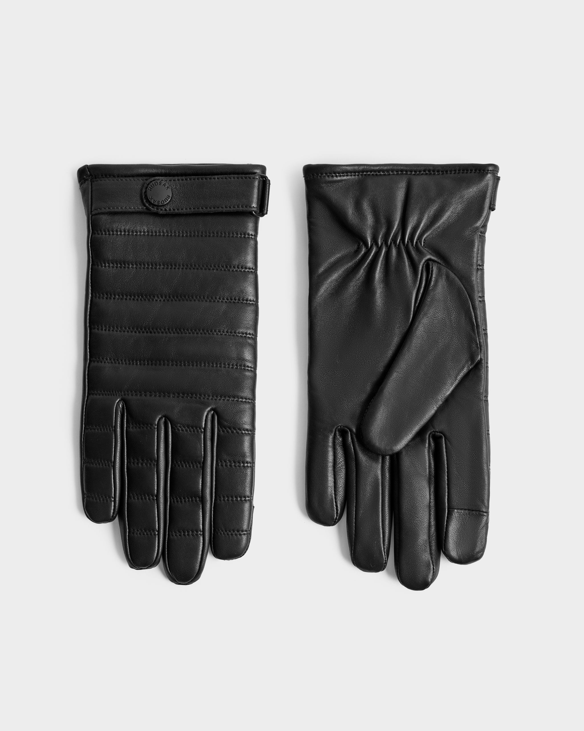 The Rudsak CORTES - 6425036 Black leather gloves, ideal winter accessories, are shown on a light gray background—one displays stitched lines and a wrist button, the other reveals the plain palm side.