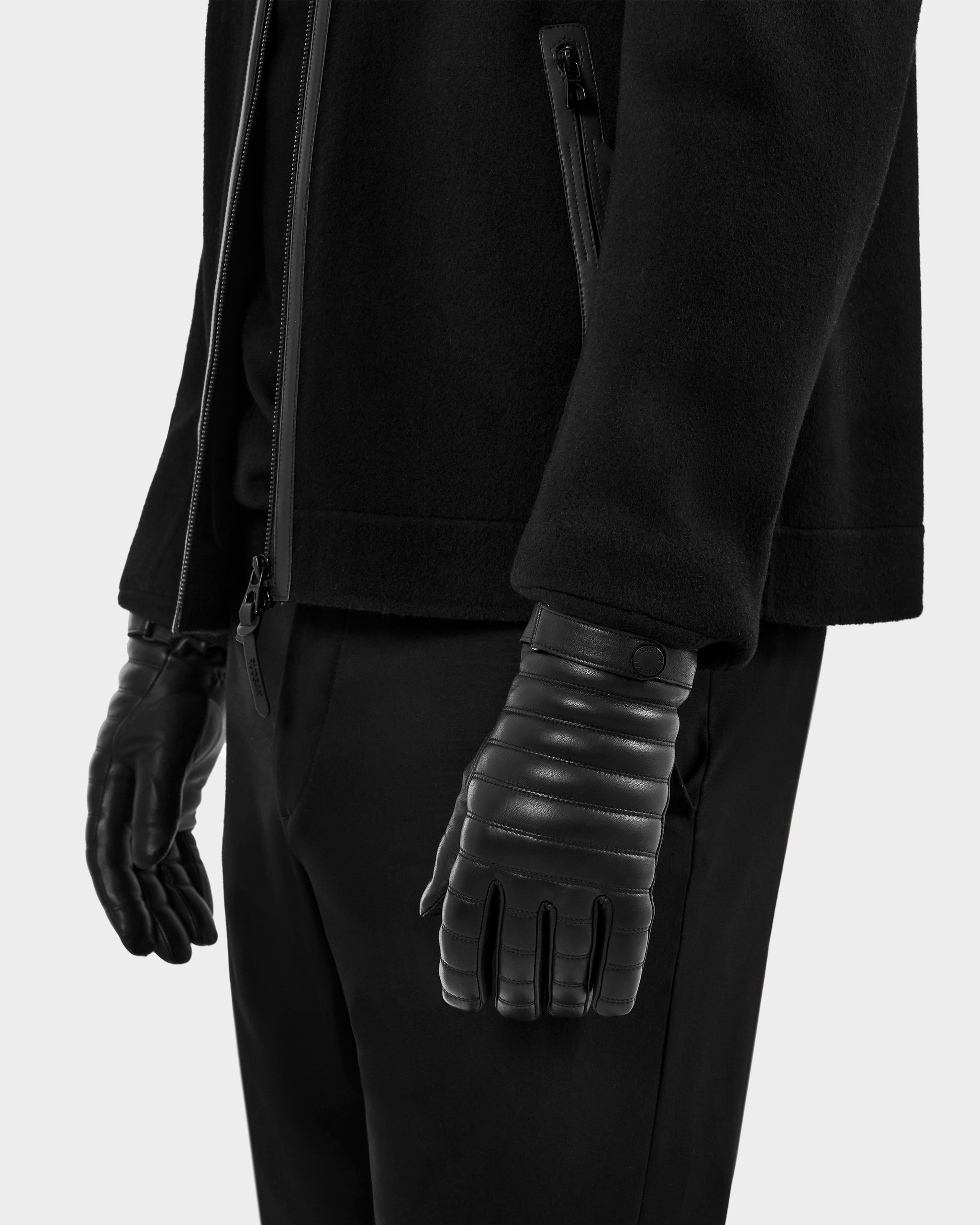 A person wearing a black CORTES - 6425036 jacket and padded leather gloves by Rudsak, paired with black pants, stands with arms relaxed at their sides against a plain light background.