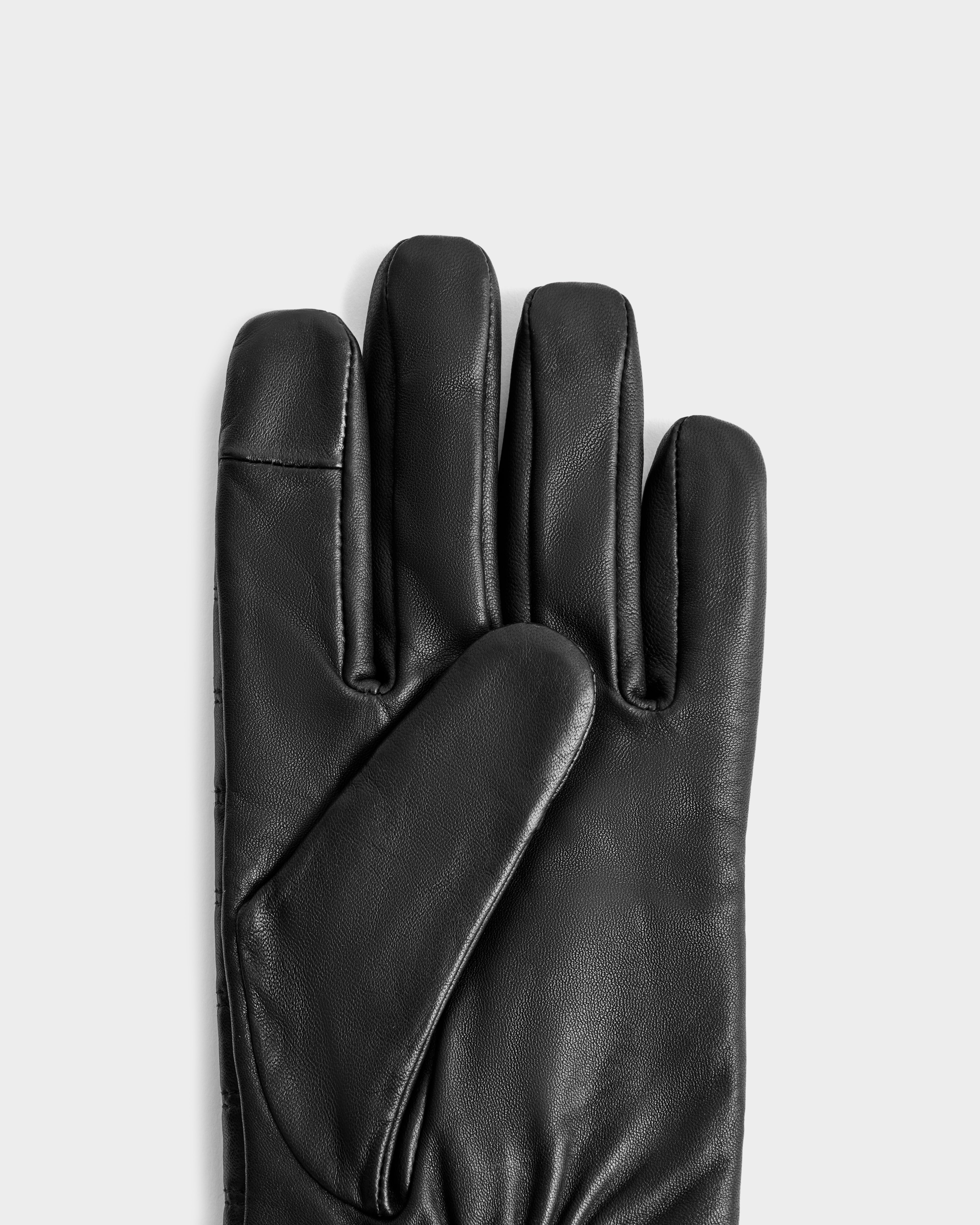 The CORTES - 6425036 Black glove by Rudsak is displayed palm up on a light gray background, vertically positioned with extended fingers and the thumb crossing the palm—an ideal black leather winter accessory.