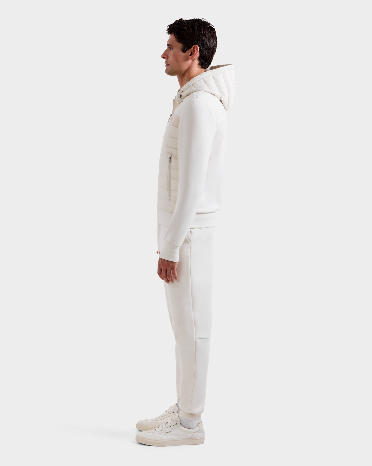 A man in profile, facing left, wears the Rudsak DEE MP - 6125673 Vanilla lightweight down jacket with waterproof zippers, matching pants, and white sneakers against a plain white background.
