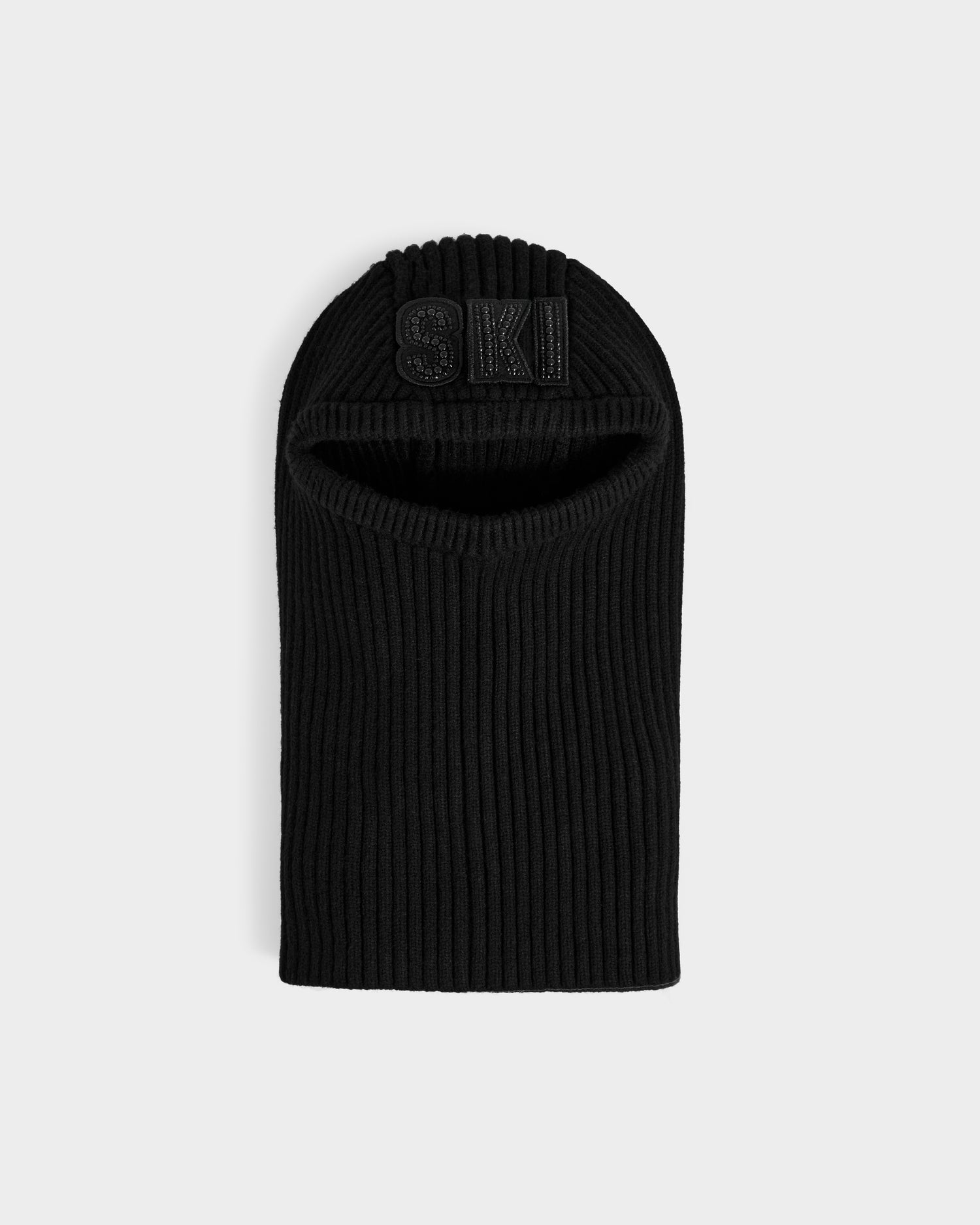 The Rudsak DIXIE - 8425551 Black is a women’s fitted knit balaclava with an open face and raised black "SKI" lettering, perfect for winter, shown laid flat on a light gray background.
