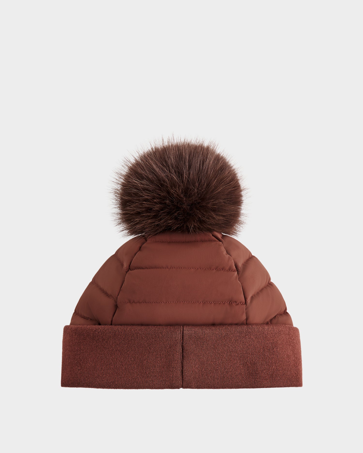 The GALA - 8424514 Rust by Rudsak is a brown quilted winter hat with a wide cuff and a large, removable faux fur pom pom, shown against a plain white background.