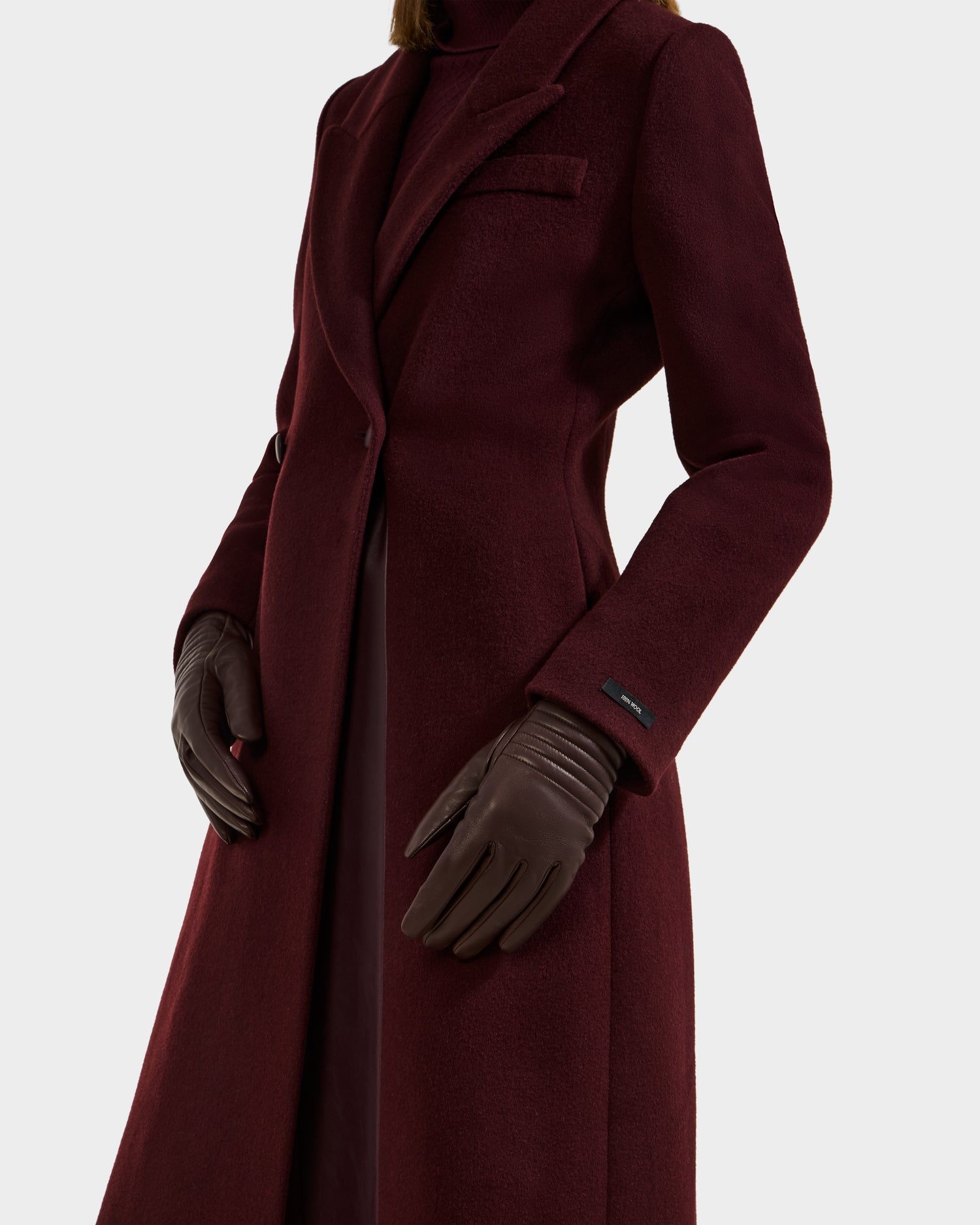 A person wearing the Rudsak GEMMA - 8425008 Espresso coat and cashmere-lined gloves stands against a white background; only the torso and upper legs are shown, spotlighting this elegant winter accessory.