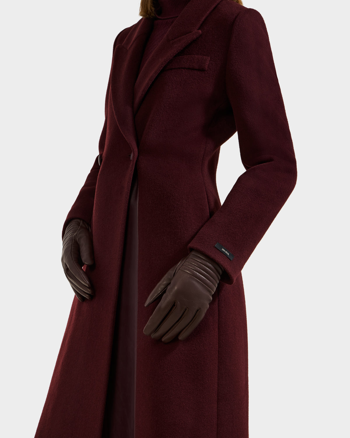 A person wearing the Rudsak GEMMA - 8425008 Espresso coat and cashmere-lined gloves stands against a white background; only the torso and upper legs are shown, spotlighting this elegant winter accessory.