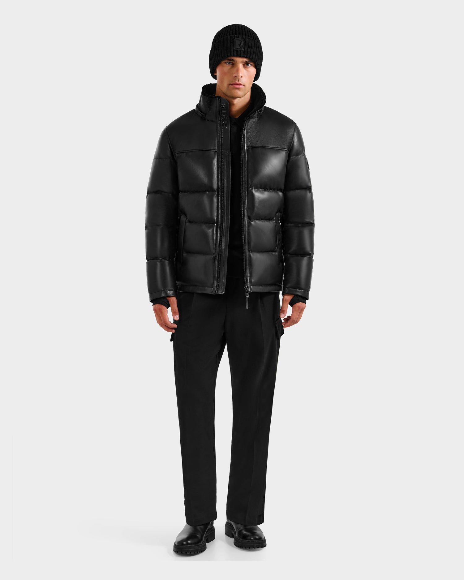 A person wearing the Rudsak JAMESON - 6125678 Black luxury winter coat stands facing forward against a plain white background.