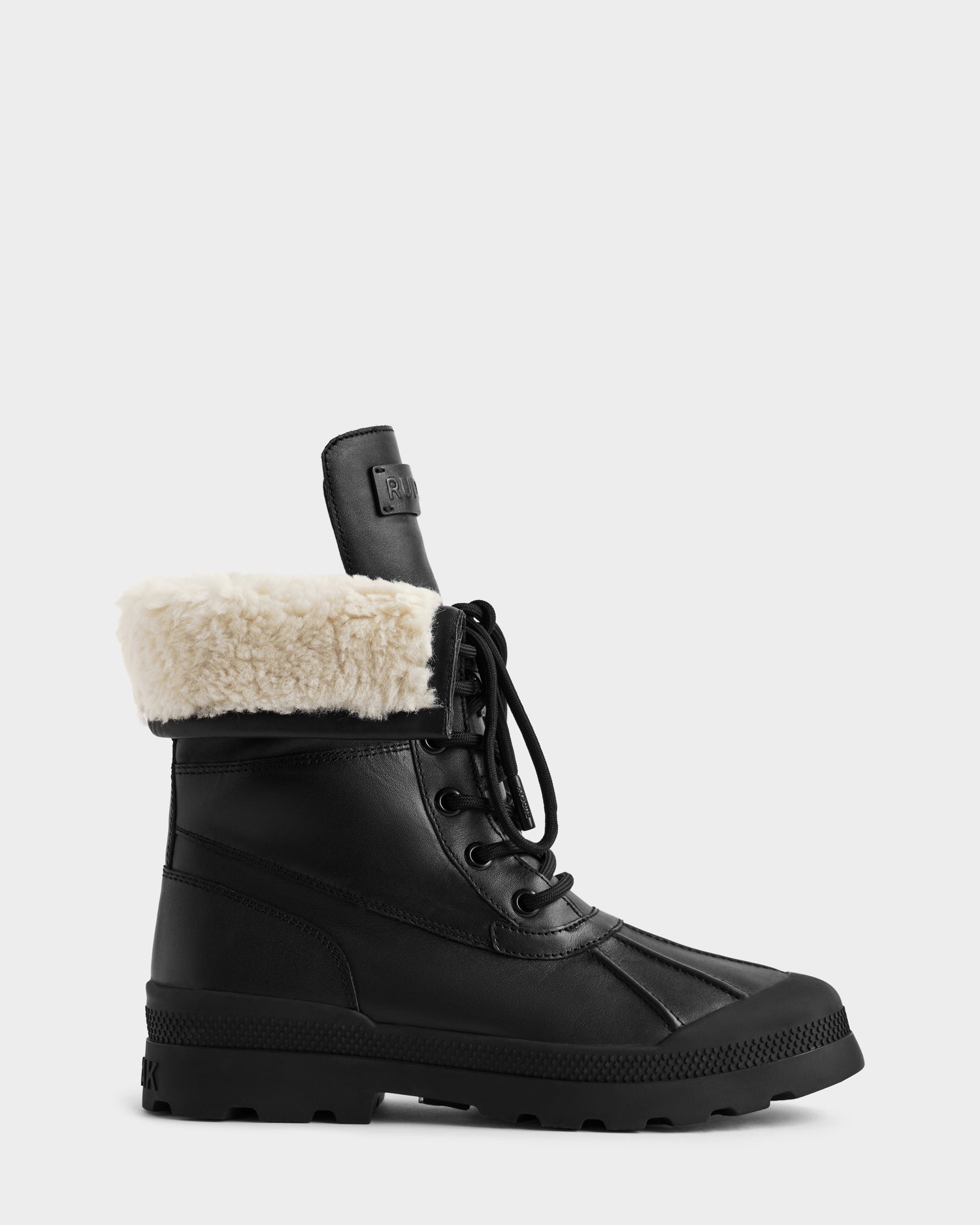 The JESI - 8225026 Black by Rudsak is a black lace-up winter boot with a thick rubber sole, raised tread, and folded-over cream faux fur lining at the top, shown against a plain light background.