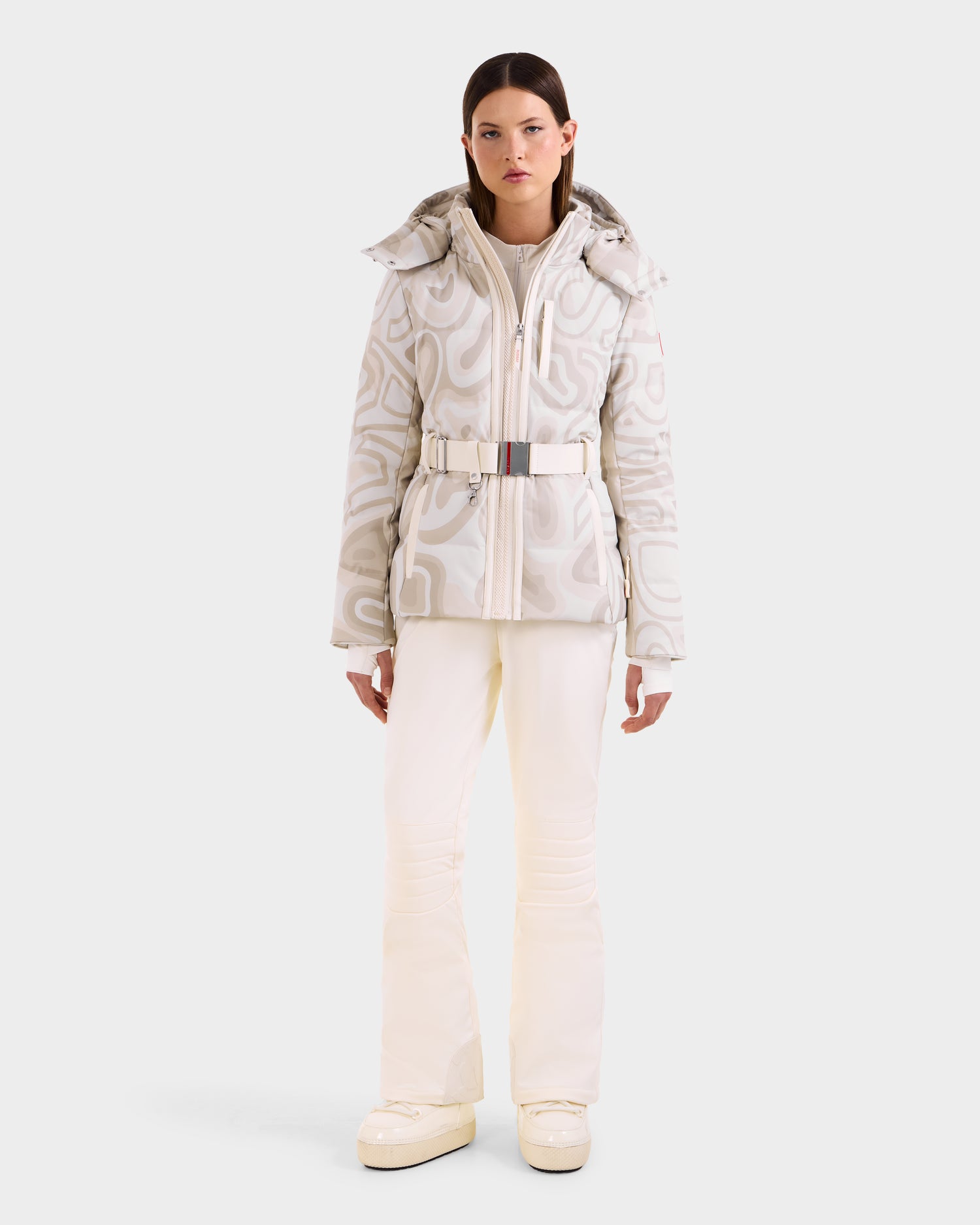 A woman faces forward wearing the Rudsak JOANNA P - 8125623 Vanilla Deja vu jacket, white pants, and platform shoes against a plain background. This item is available for pre-order and ships by November 30th.