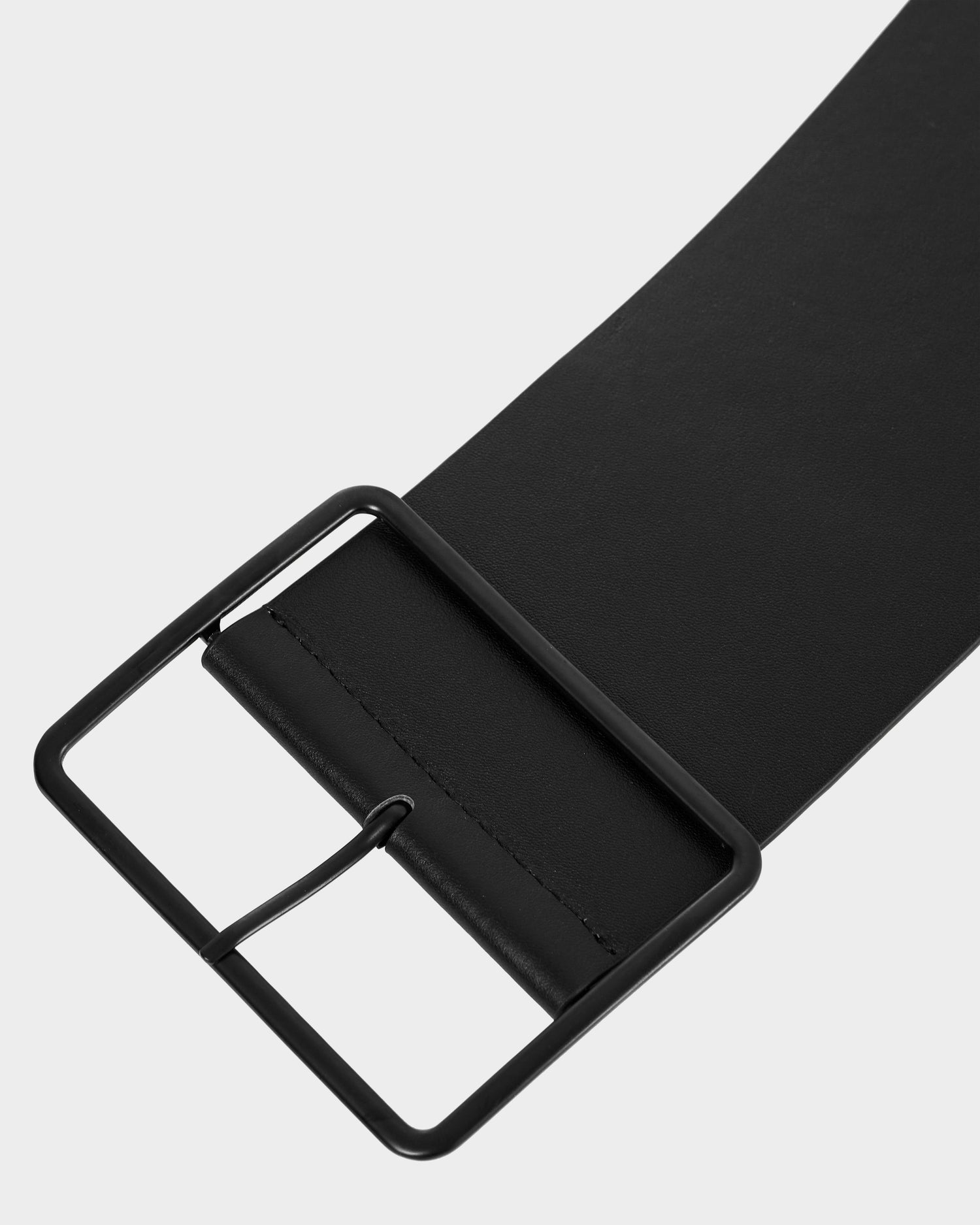 Close-up of the JOCELYN - 8425040 Black women’s leather belt by Rudsak, featuring a wide black strap and an adjustable square black metal buckle, set against a plain light grey background.