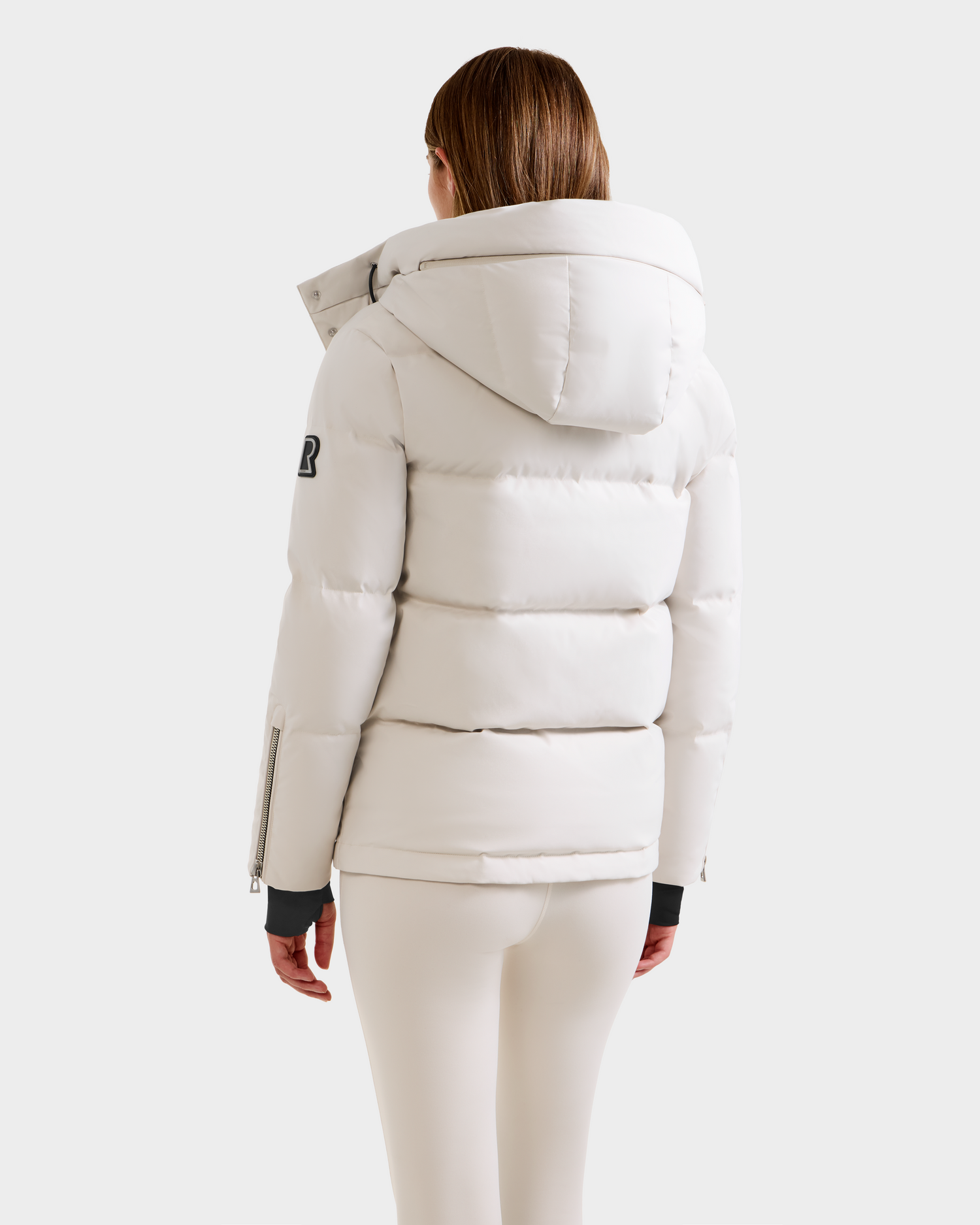 A person with straight brown hair is seen from behind wearing the Rudsak JOON H - 8125586 Vanilla women’s down jacket and matching white pants, set against a plain light background.
