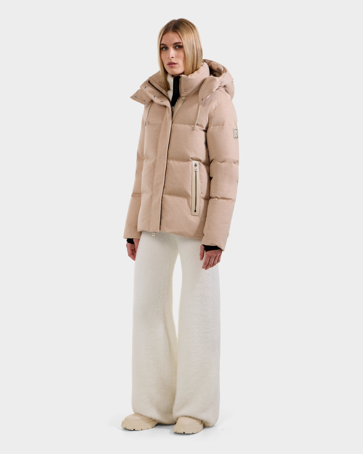 A woman wearing the Rudsak JOON W - 8125566 Heather Beige jacket with a hood, wide-leg cream pants, and matching beige shoes stands against a plain white background.