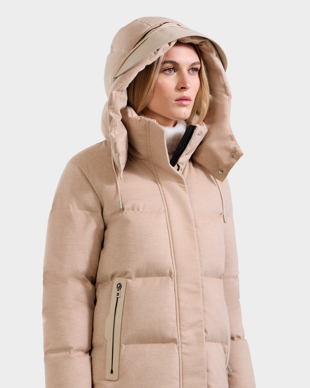 A woman wears the Rudsak JOON W - 8125566 jacket in Heather Beige, featuring a hood, high collar, and zippered pockets, standing slightly to the side with a neutral expression.