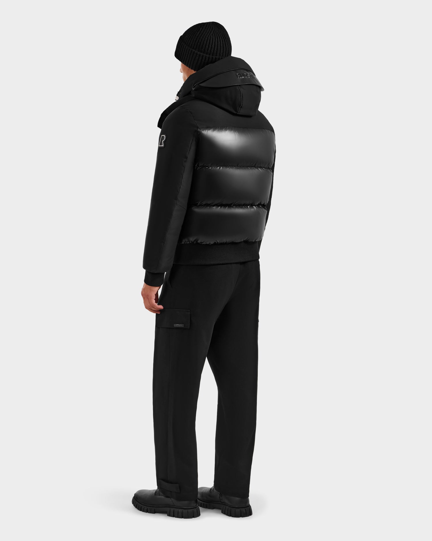 A person wearing the Rudsak JORDY H - 6125689 Black jacket is standing and facing away from the camera against a plain light gray background.