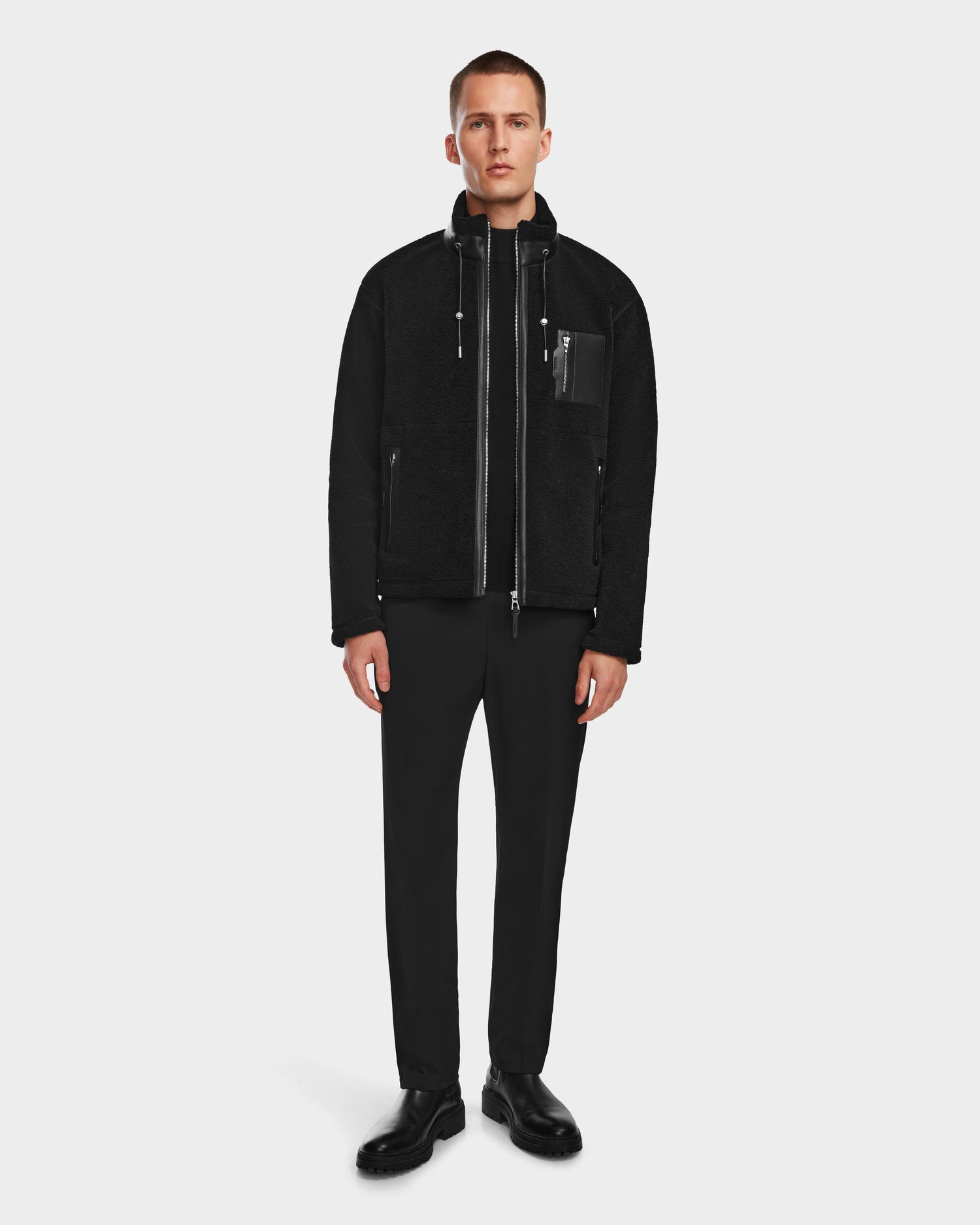 A man faces forward wearing the Rudsak JOSEPH - 6524535 Black zip-up jacket, paired with black pants and shoes, set against a plain white background.