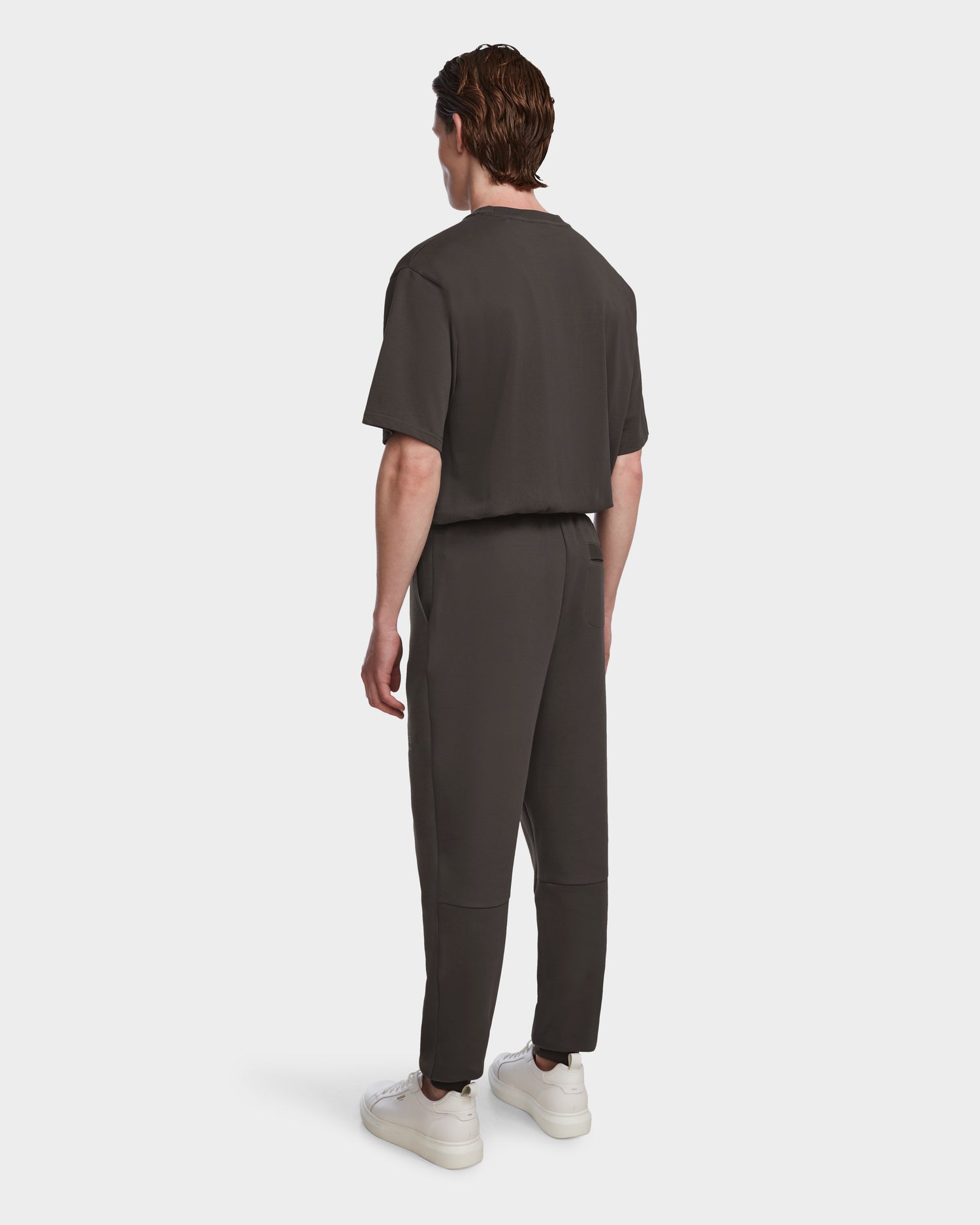 A person with short brown hair, facing away, wears the Rudsak JOSS - 9524009 jogger set in grey (size M) and white sneakers against a plain white background.