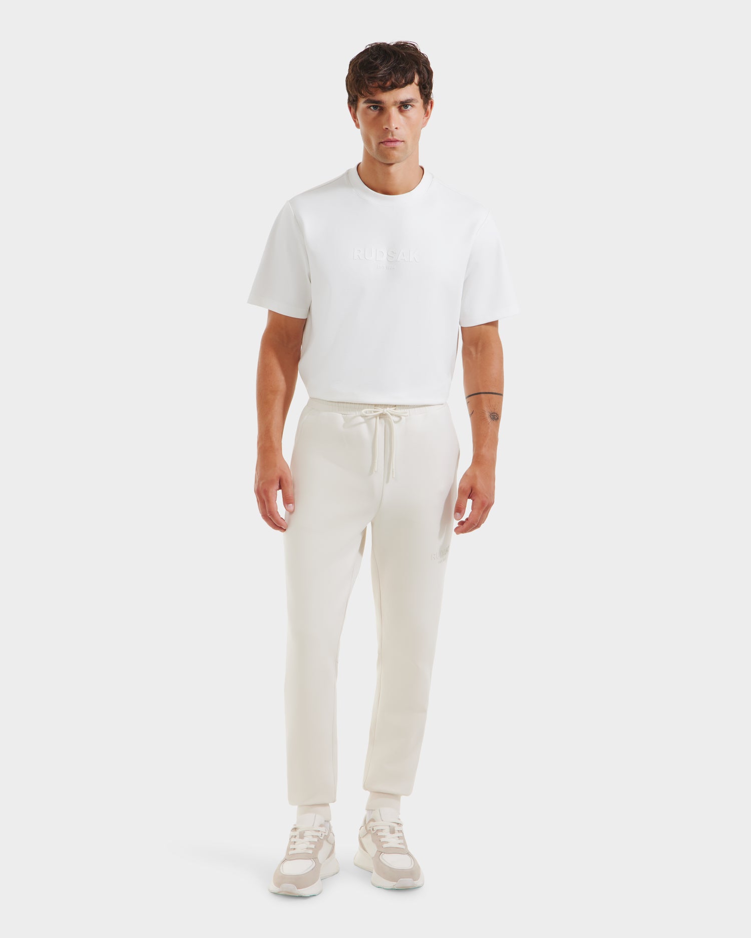 A man in the Rudsak JOSS - 9524009 Vanilla M cotton-blend unisex jogger paired with a crisp white shirt.