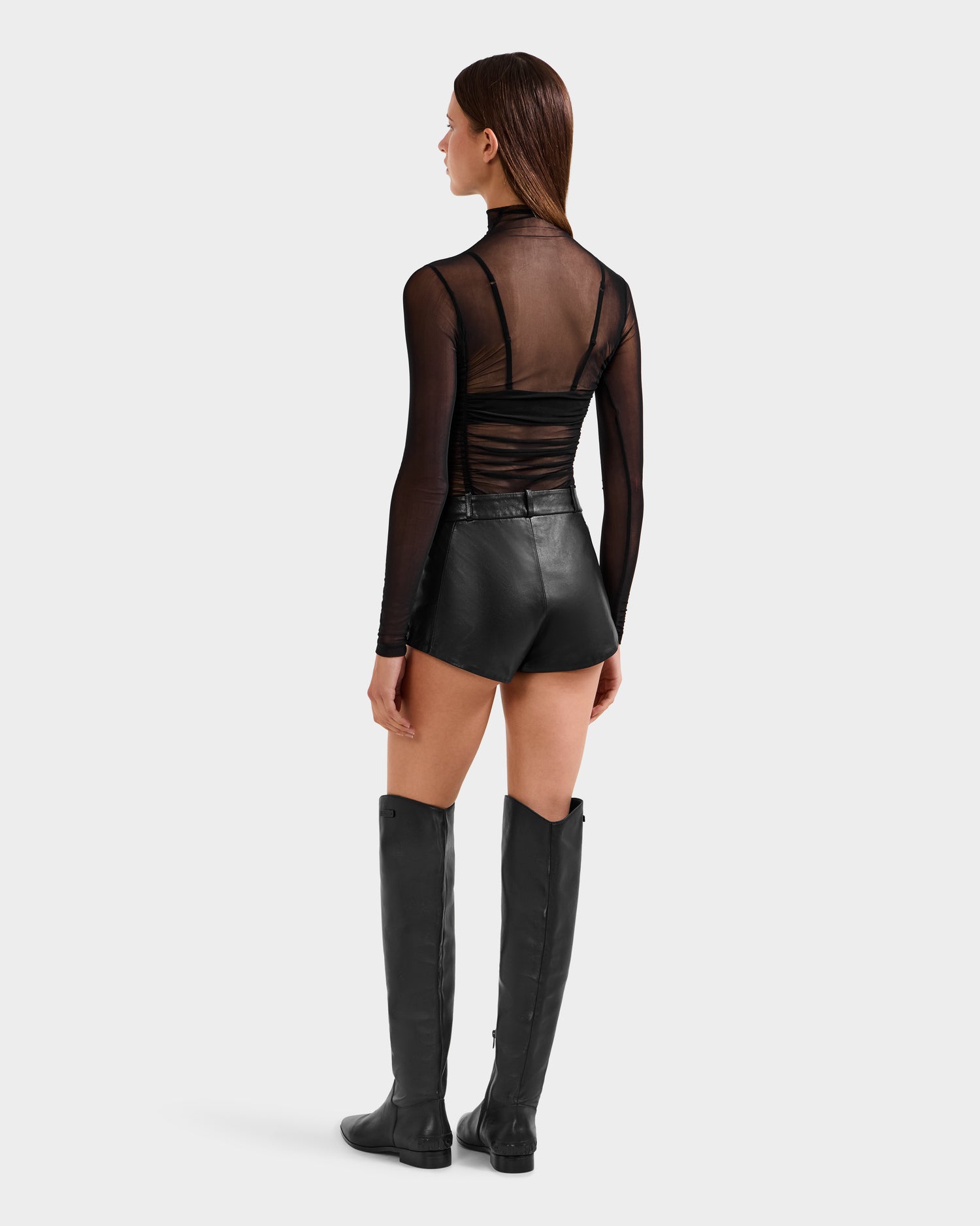 A woman wears the KENNEDY - 8525610 Black shorts by Rudsak with black boots, exemplifying bold womens fashion.