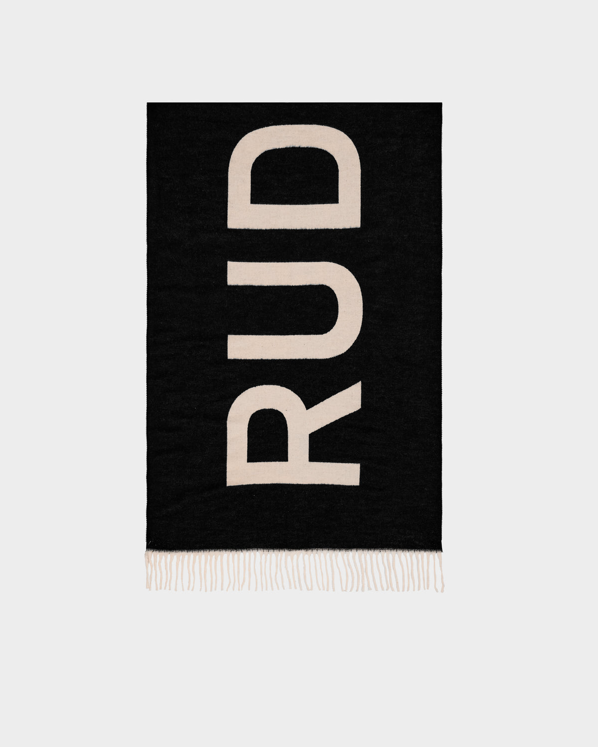 The Rudsak LEV - U425506 Black scarf is a black rectangular, reversible unisex accessory with large beige “RUD” letters, short beige fringe, and a stylish look—shown on a light gray background.