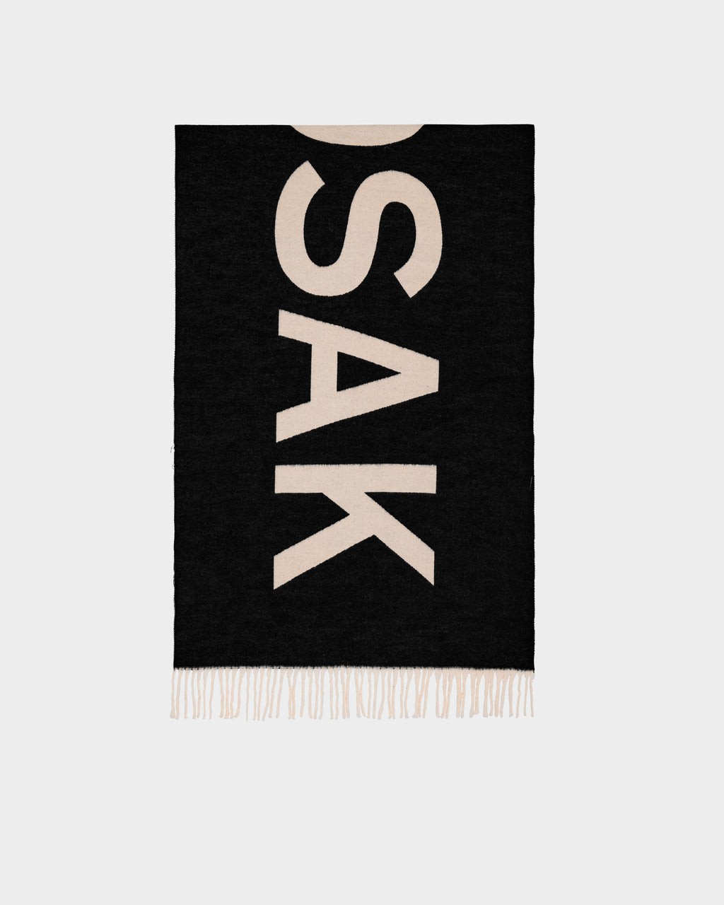 The Rudsak LEV - U425506 Black reversible unisex scarf features large beige “SAK” letters, fringed edges, and is shown on a light grey background—a stylish cold-weather accessory.