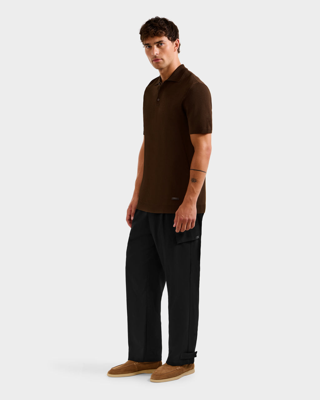 A man with short brown hair and a neutral expression wears the Rudsak MAISEN - 6524518 Mocha polo shirt against a plain background, paired with black pants and brown shoes, highlighting modern men's wardrobe essentials.