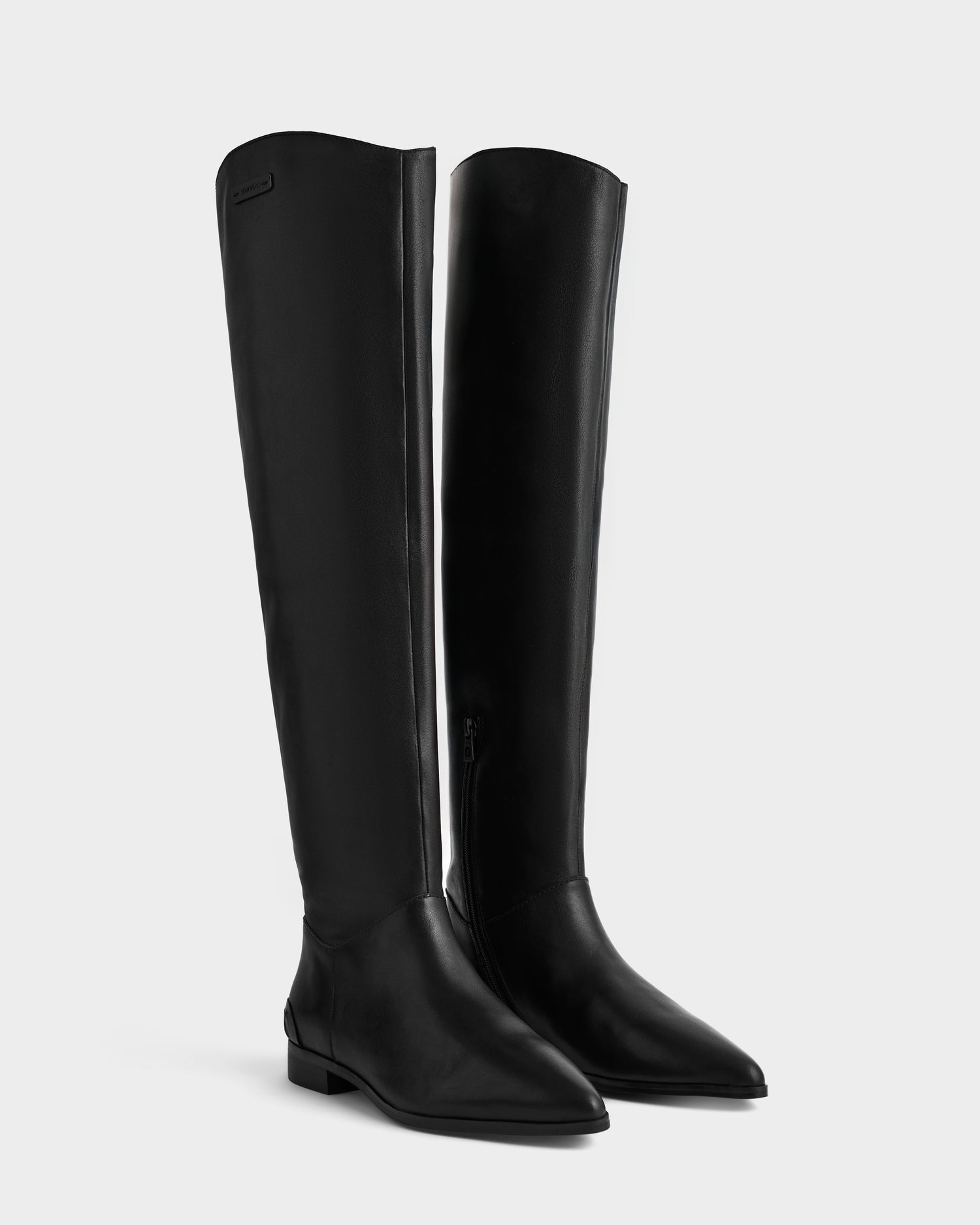 The MARSALLA - 8225033 Black by Rudsak: sleek black knee-high flat riding boots, crafted from smooth leather with pointed toes and side zippers, shown against a plain light gray background.