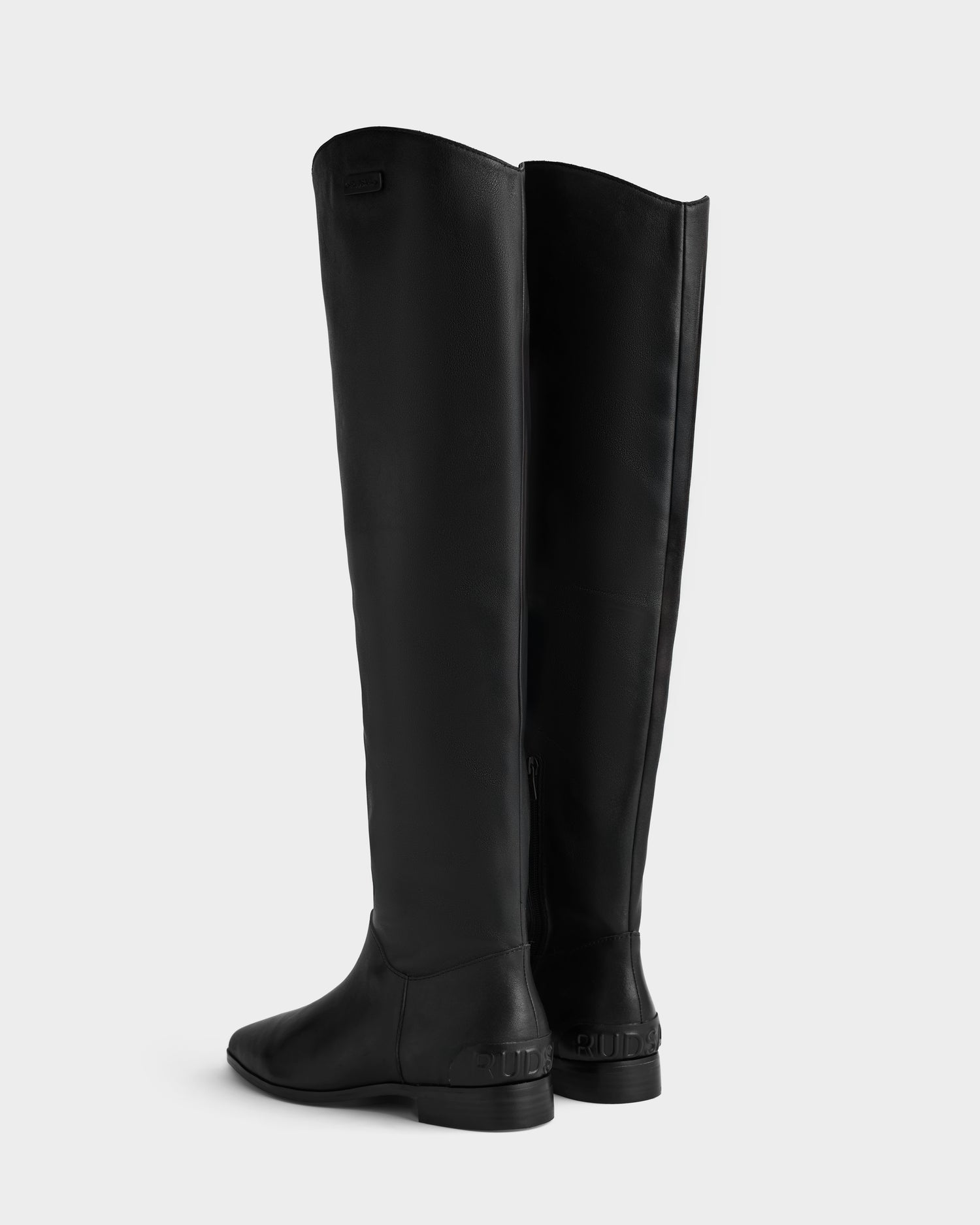 The MARSALLA - 8225033 Black women’s high-shaft leather boots by Rudsak feature low heels and a tall black silhouette, shown from the back and side against a plain white background.