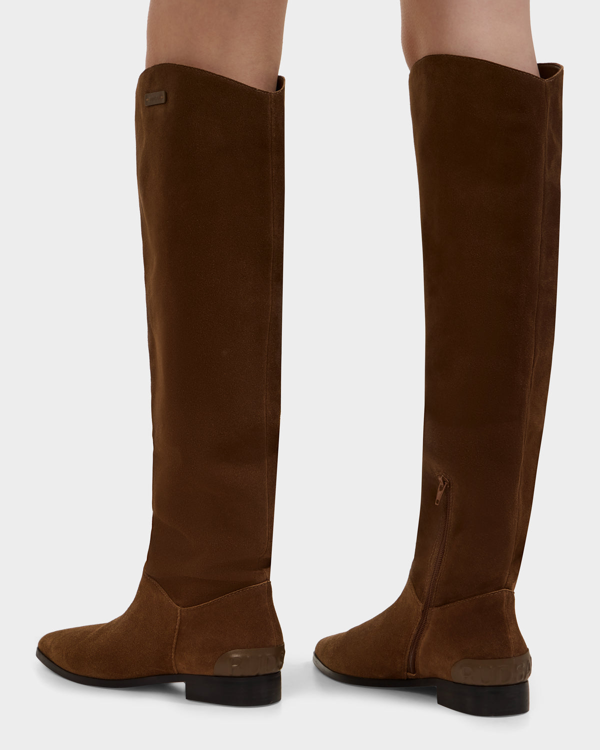The MARSALLA - 8225033 Mocha boots by Rudsak feature a tall, mocha suede design with low heels and side zippers. These elegant high-shaft women's boots create a classic, versatile look when worn with bare legs.