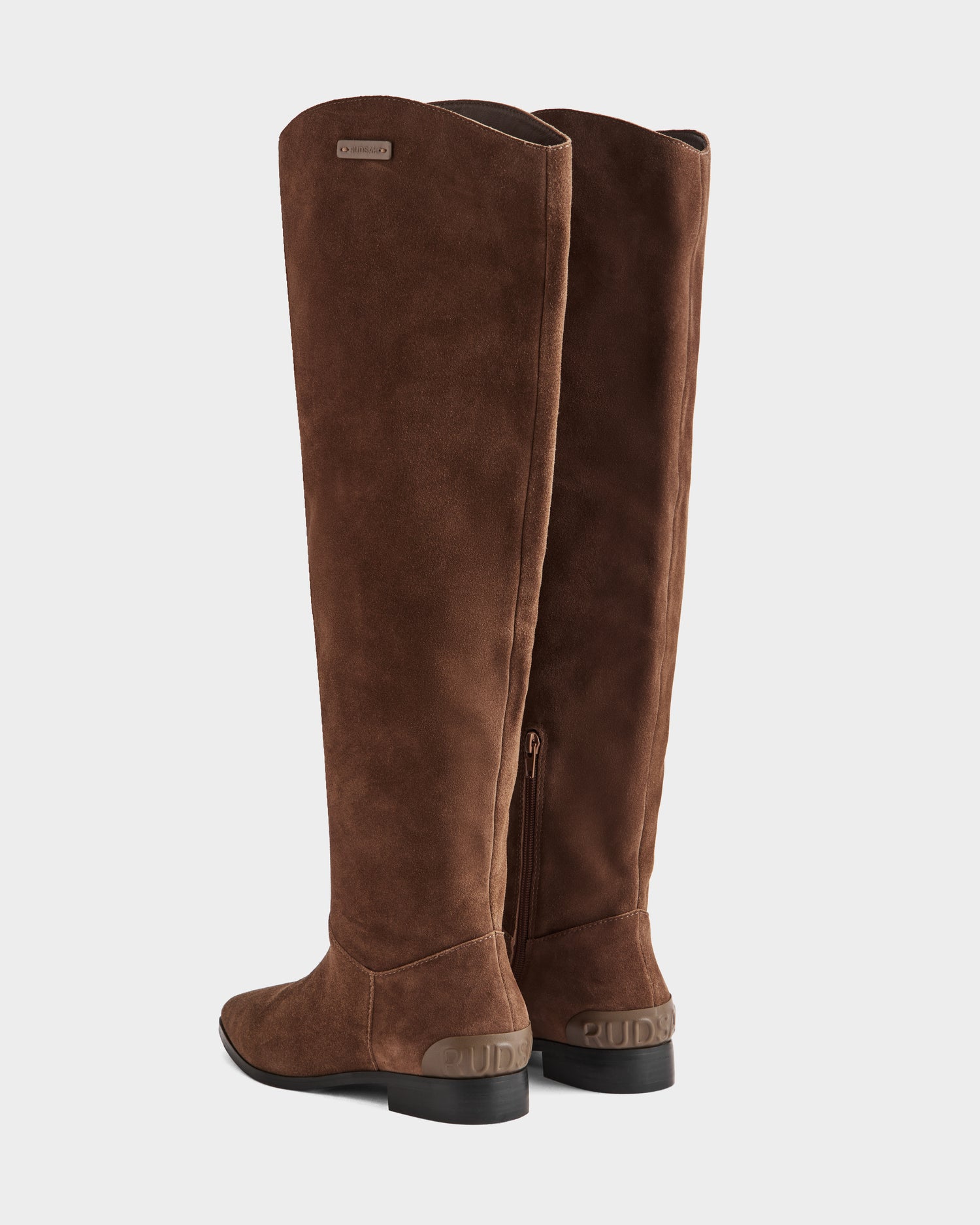 The Rudsak MARSALLA - 8225033 Mocha women’s tall brown suede riding boots feature low black heels and subtle branding on the heel and upper side, displayed against a white background.