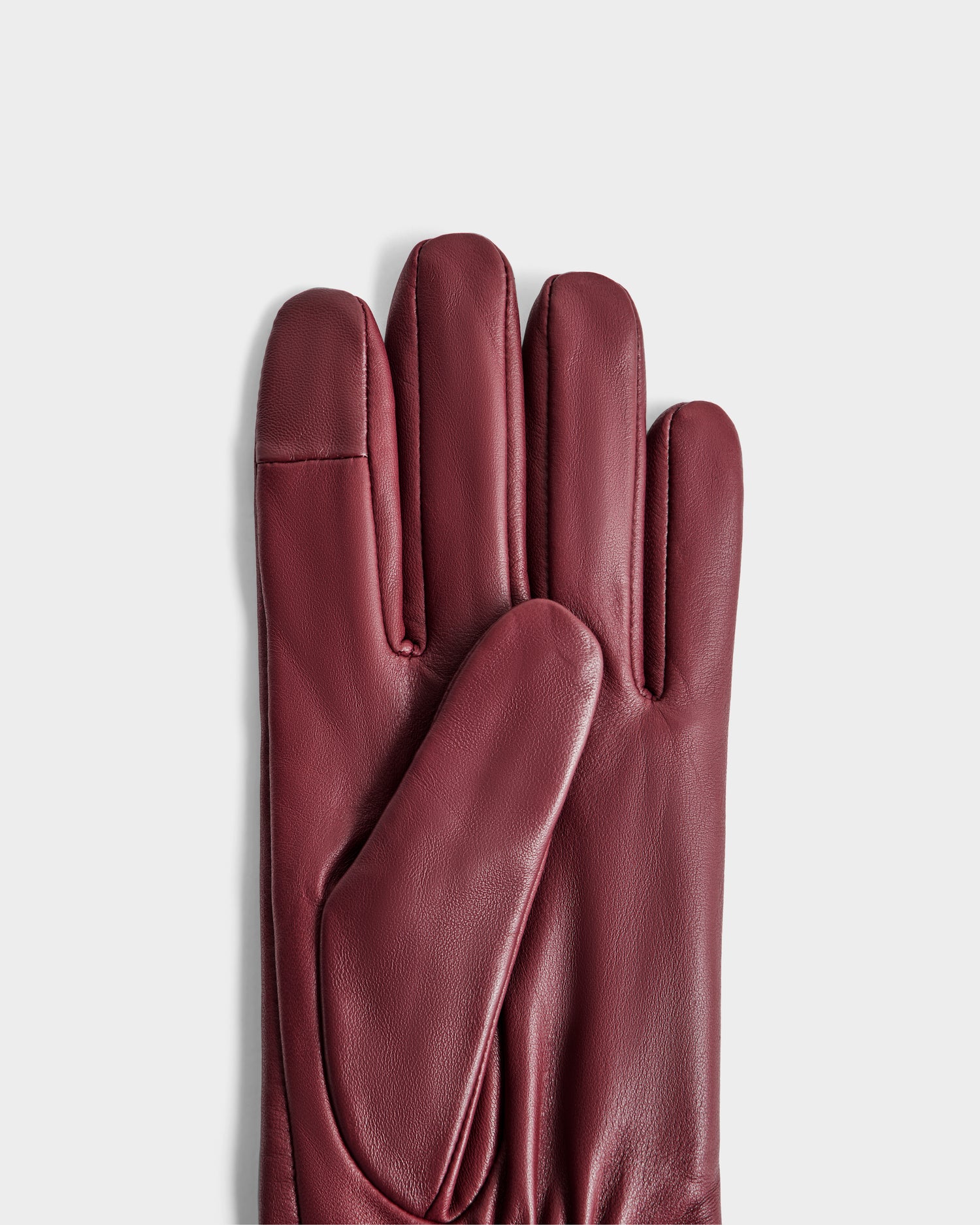 The Rudsak MEGAN - 8425541 Bordeaux women's gloves, crafted in smooth burgundy leather with a classic, elegant design, are neatly stacked on a plain light gray background.