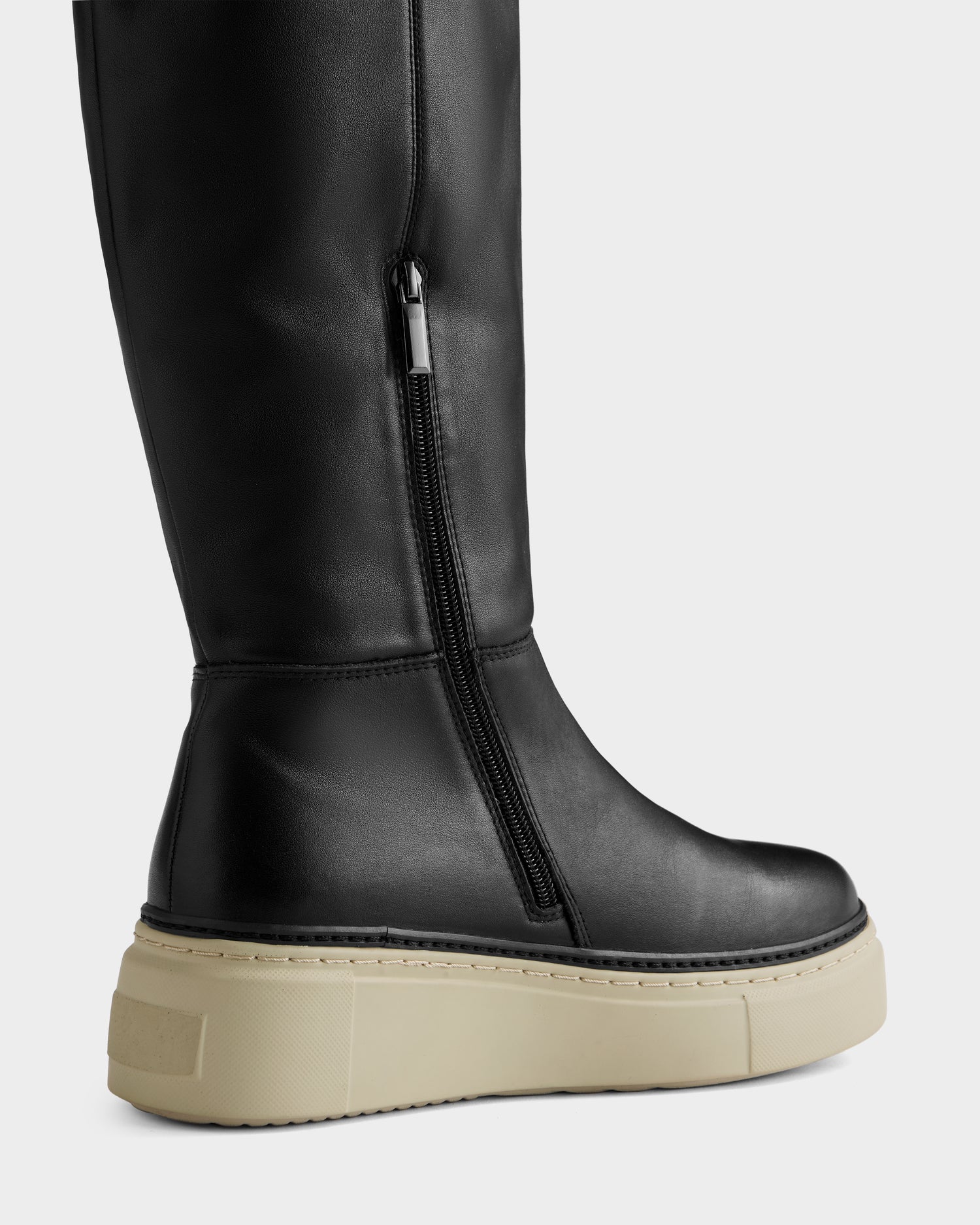 A close-up of the Rudsak MIKIE L - 8225580 Black knee-high boot, featuring a side zipper and thick beige platform sole, set against a plain light gray background.