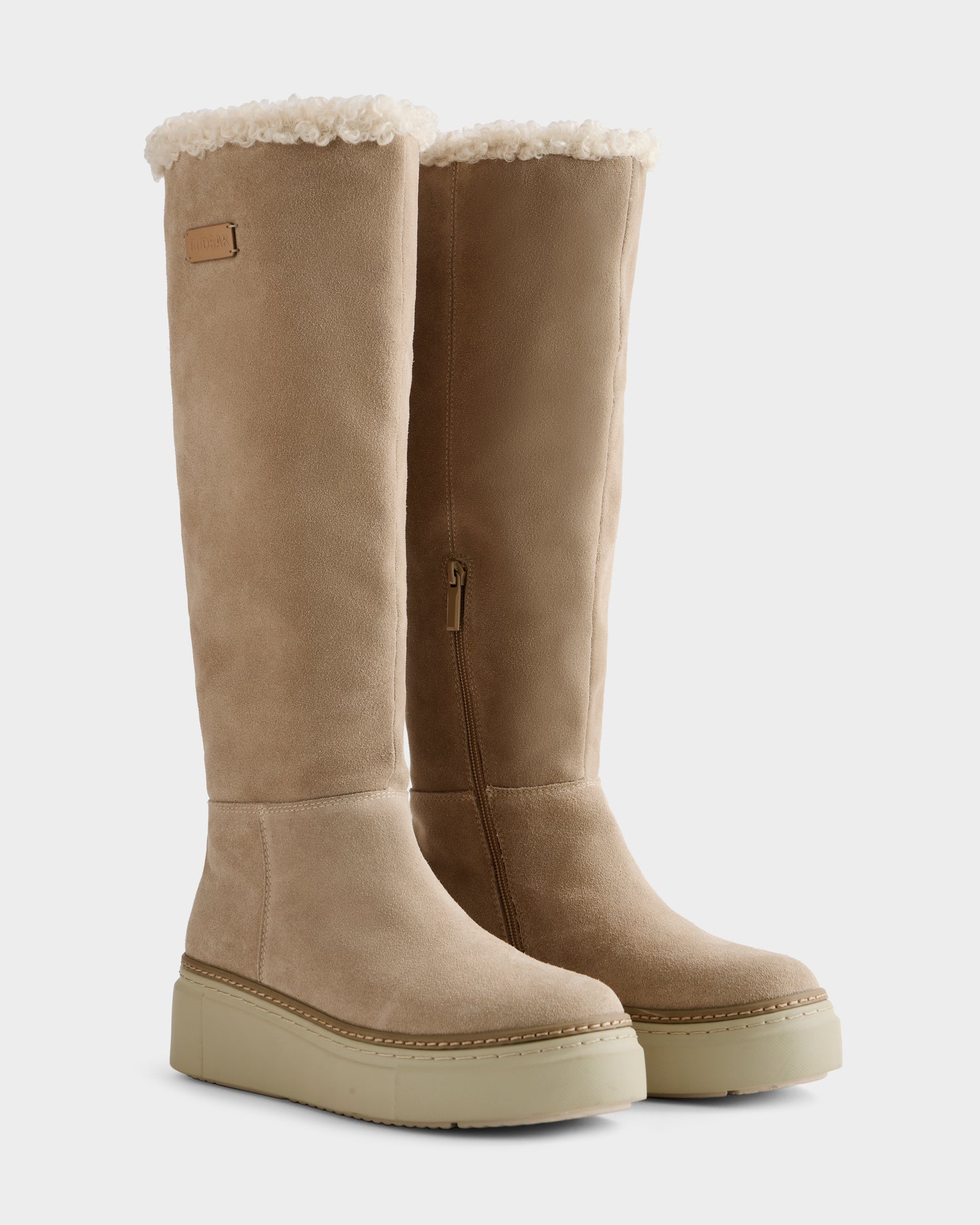 The MIKIE - 8225579 Almond by Rudsak is a women’s tan suede foldover shearling boot with thick light soles, visible shearling lining, side zipper, and decorative stitching—perfect for cold-weather style.