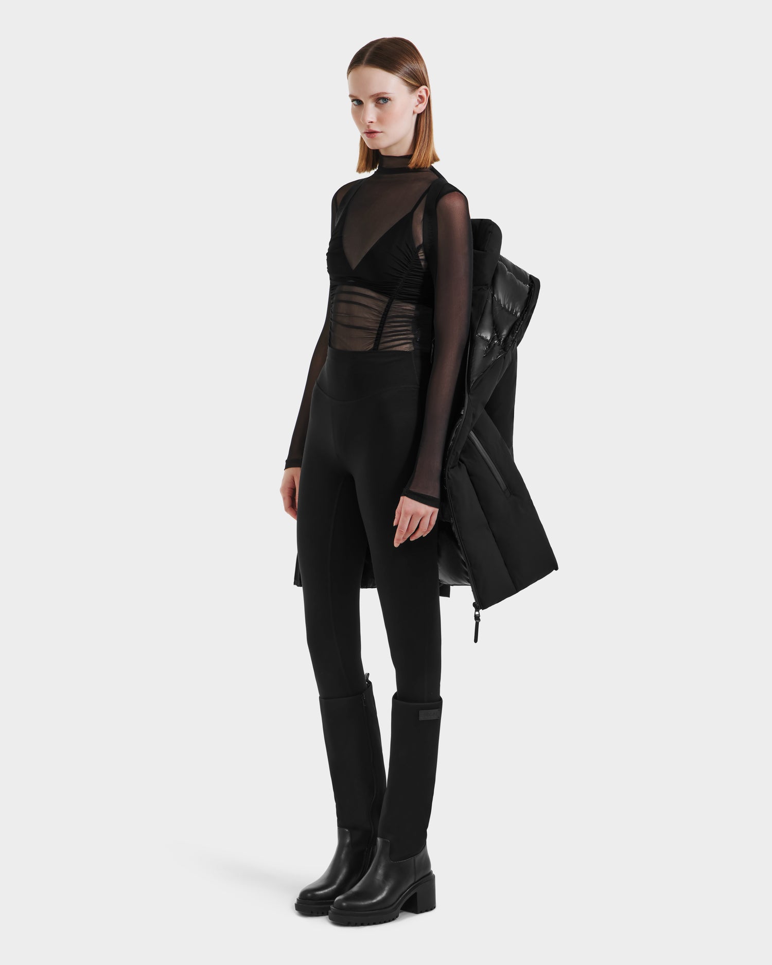 A woman with straight, shoulder-length hair and a neutral expression stands against a plain background, wearing the Rudsak MODA M - L125555 Black winter coat draped over her shoulders.