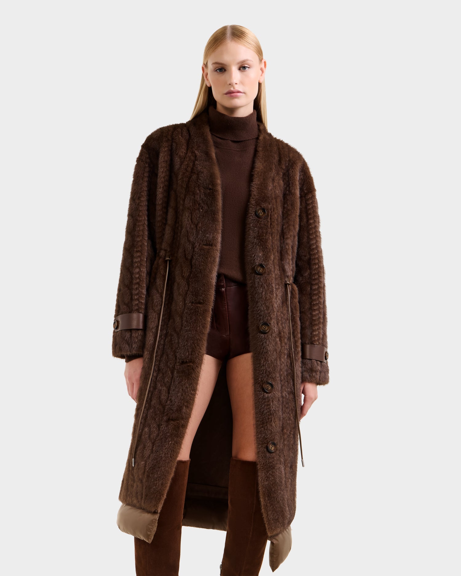 A woman models the Rudsak ORIANA - 8125545 Mocha faux fur coat with a brown turtleneck, shorts, and knee-high boots against a white background.
