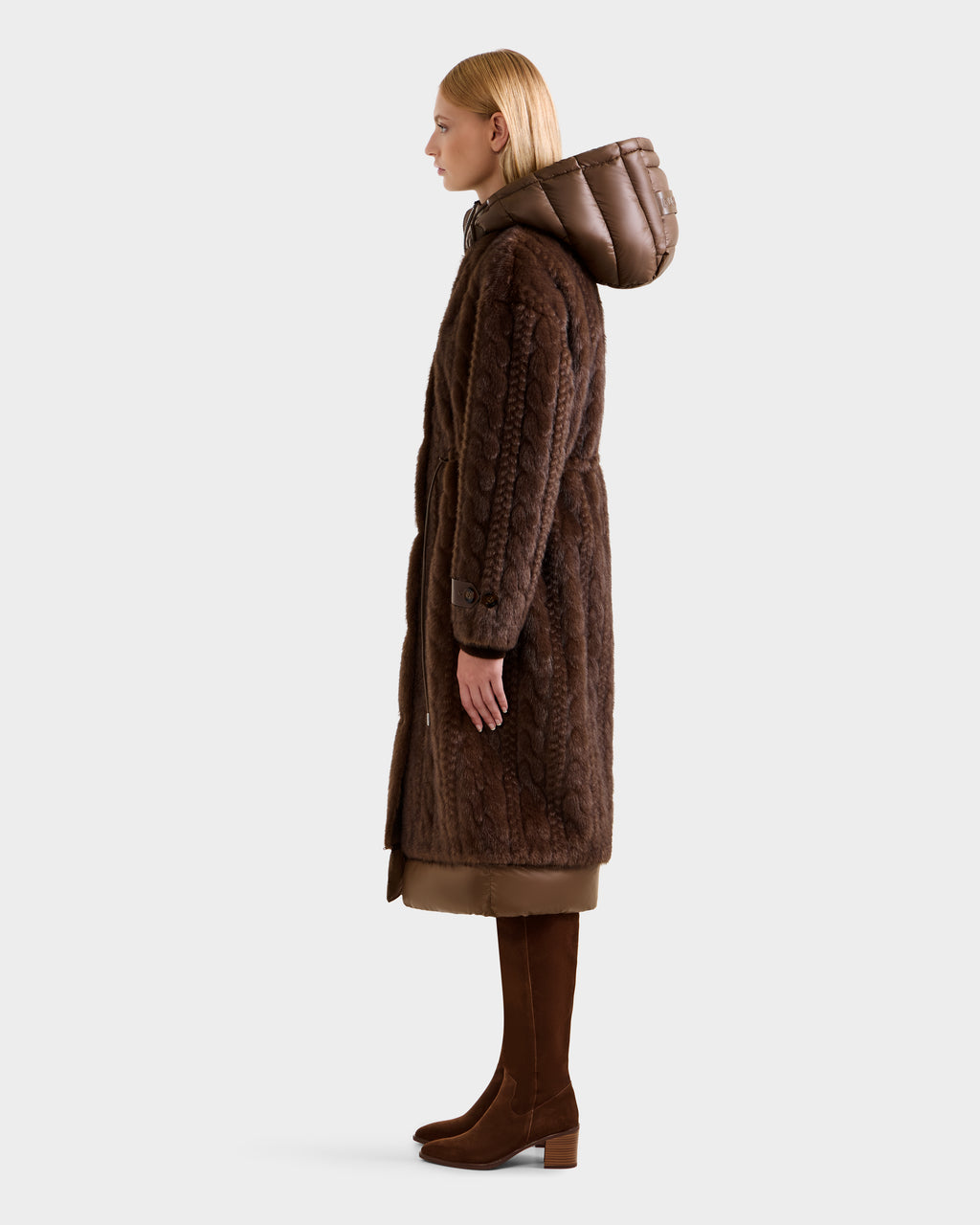 A person in profile wears the Rudsak ORIANA - 8125545 Mocha women’s faux fur coat with vegan leather trims, a brown skirt, and knee-high boots against a plain light background.