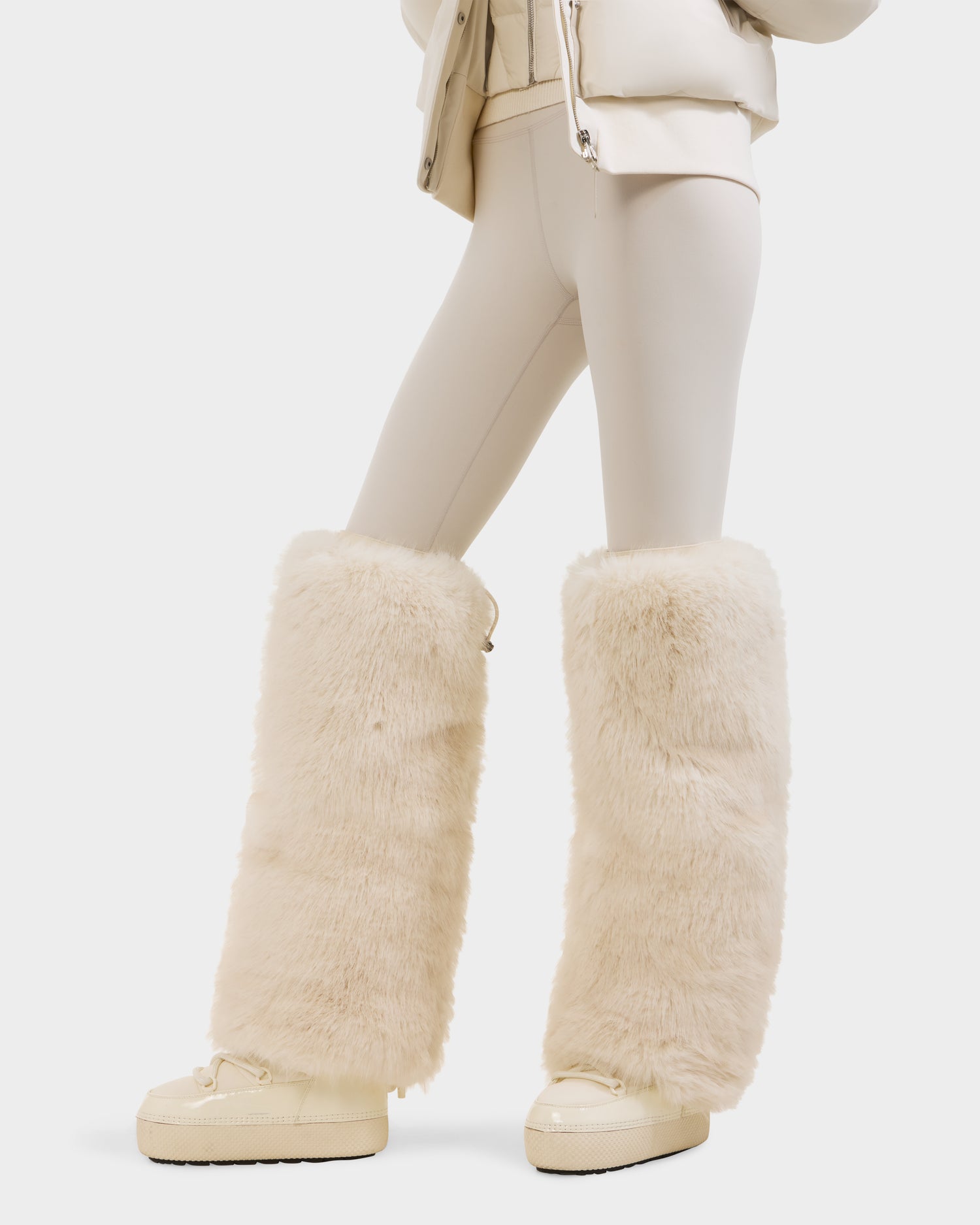 Wearing the Rudsak PAIGE - 8425534 Vanilla leggings, this person pairs them with matching platform shoes and tall faux fur leg warmers for an après-ski chic look against a white background.