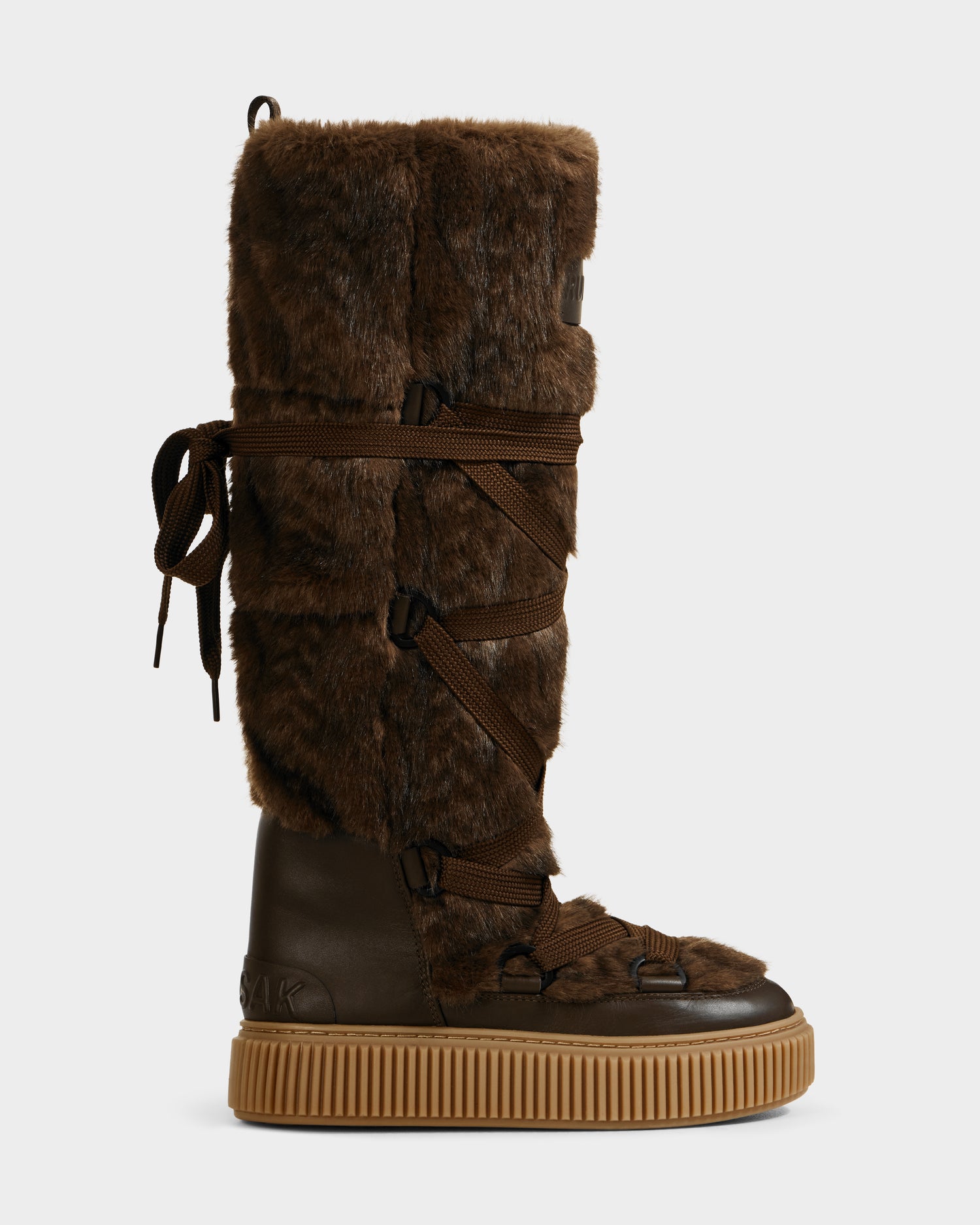 The Rudsak PALERMO C - 8225546 Mocha is a tall women’s faux fur winter boot with cozy brown covering, crisscross laces, a brown rubber sole, and a pull loop—perfect for chilly days.