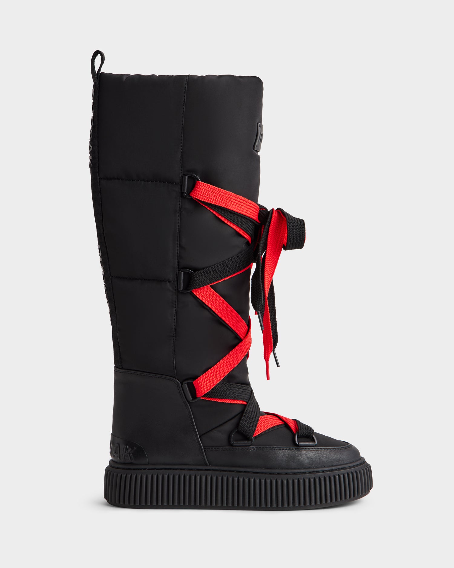 The Rudsak PALERMO - 8225030 Black is a black women’s knee-high winter boot with bold red crisscross laces, a thick sole, padded insulation, water-resistant material, and a top shaft loop.