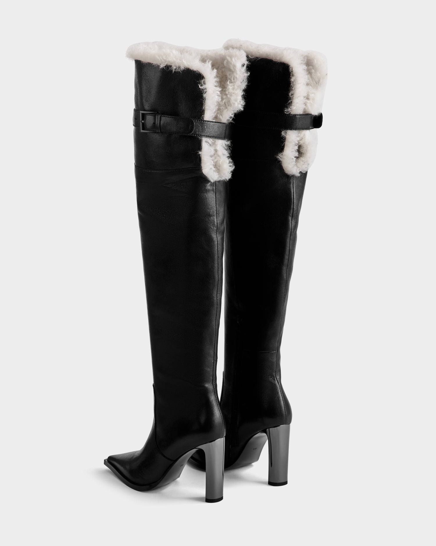 The PERNA - 8225555 Black boots by Rudsak are tall leather shearling cuff boots with black heels, visible white shearling at the top and seams, and side buckle straps—perfect as standout winter footwear.