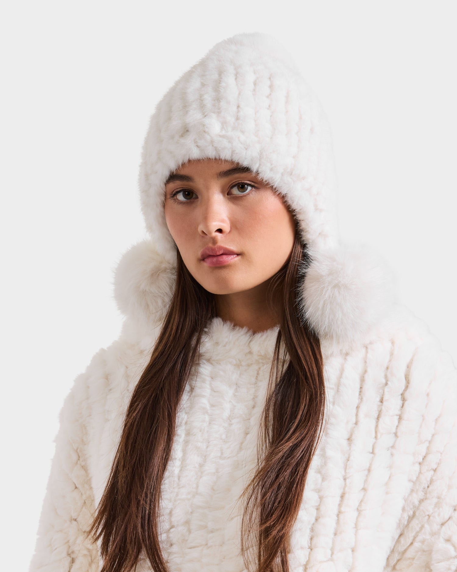 A woman wearing the Rudsak PIA - 8425547 Iceland women’s faux fur hat with pom-poms and a matching textured white sweater looks directly at the camera against a plain light background.