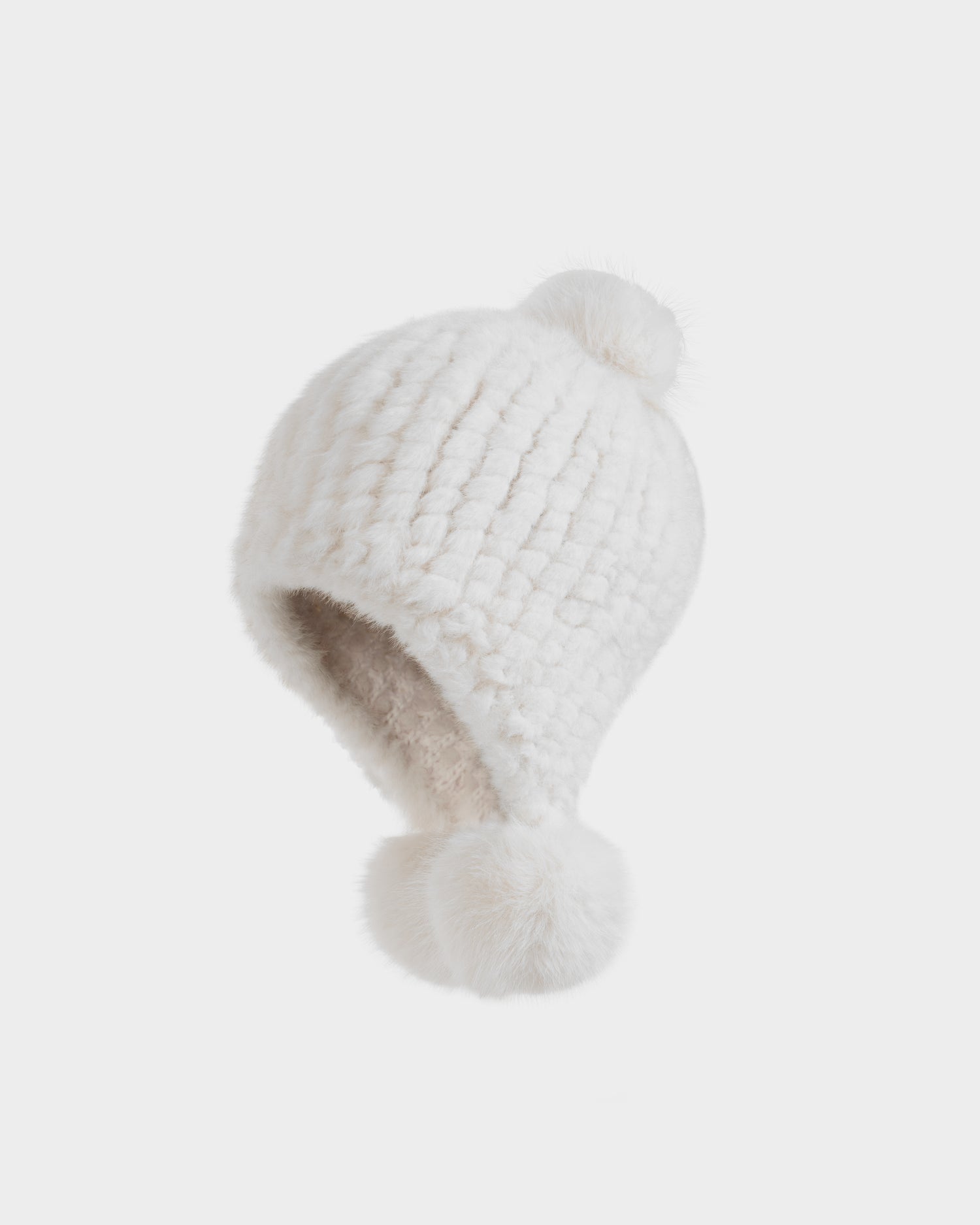The Rudsak PIA - 8425547 Iceland is a white chunky-knit women’s winter hat with faux fur, featuring fluffy pom-poms on top and the chin strap, shown against a plain white background.
