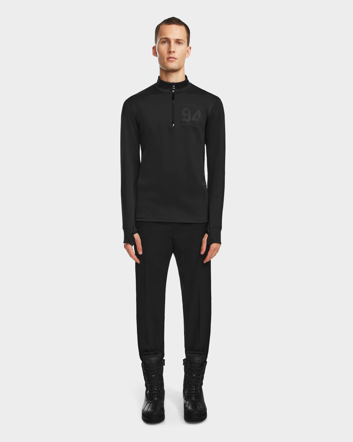 A man faces forward in the Rudsak RALI - 6524522 Black men’s active top, black pants, and black lace-up boots—showcasing ideal ski layering against a plain white background.