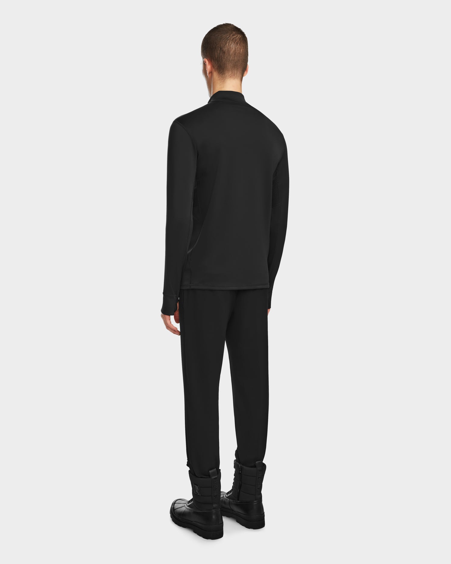 Wearing the RALI - 6524522 Black pants by Rudsak, a short-haired person stands facing away against a light gray background—ideal inspiration for ski layering or winter sports style.