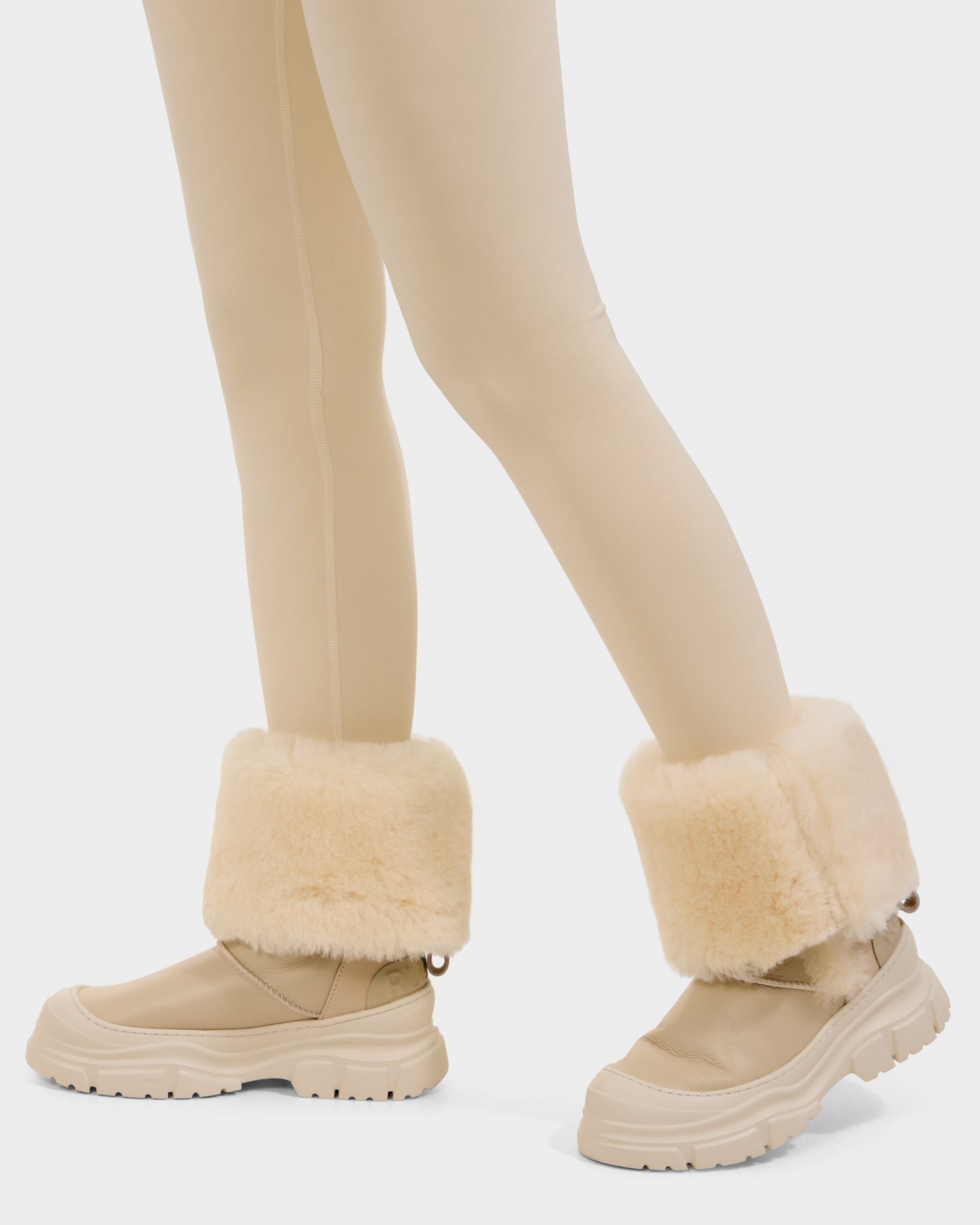 A person wearing beige leggings and Rudsak RAVENNA - 8225031 Vanilla women’s winter boots with thick, fluffy, light beige faux fur cuffs. Only the legs and feet are visible against a plain background.
