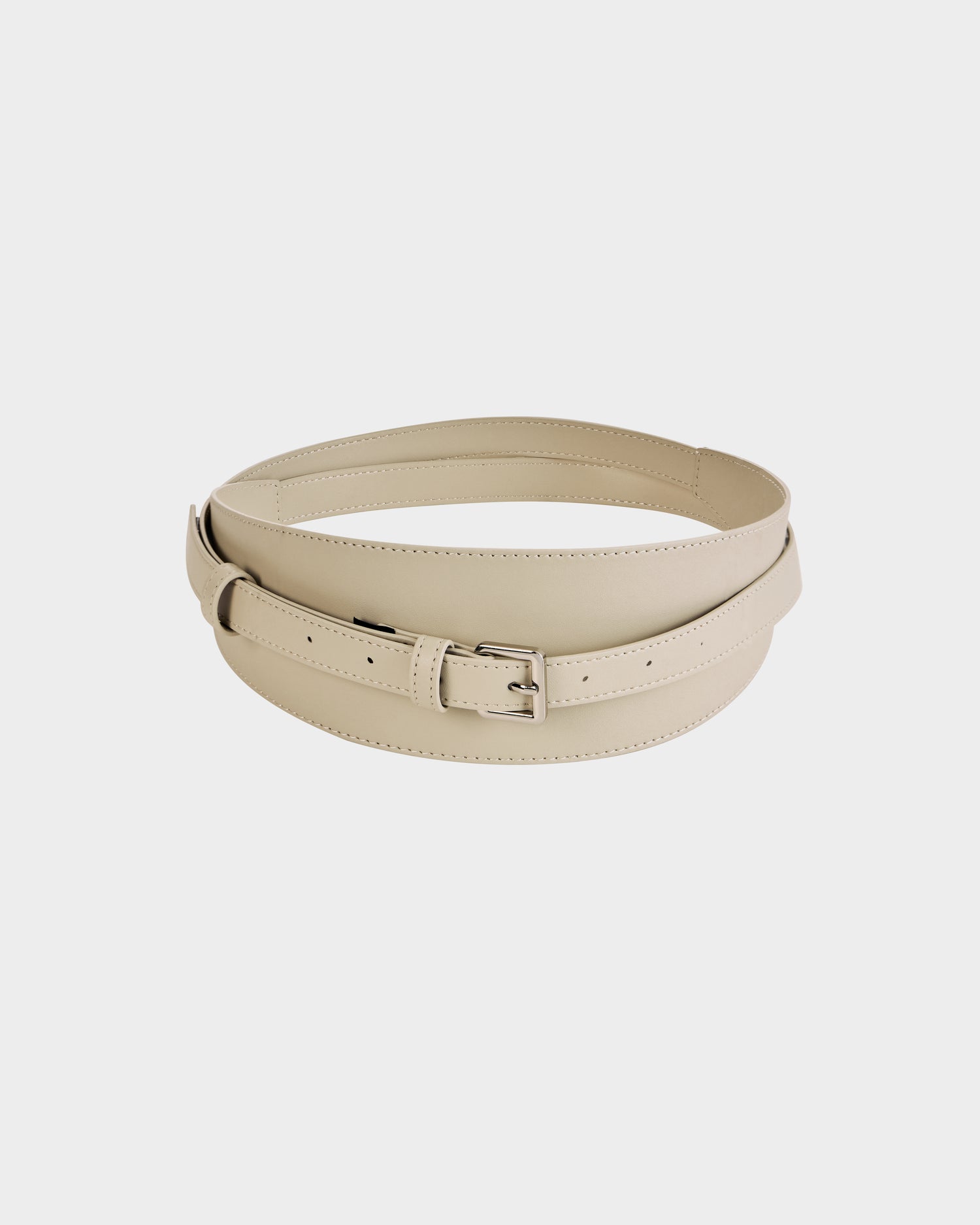 The Rudsak RENA - 8425039 Vanilla belt, crafted from beige leather and featuring a silver buckle, is displayed in a circular shape on a plain white background.
