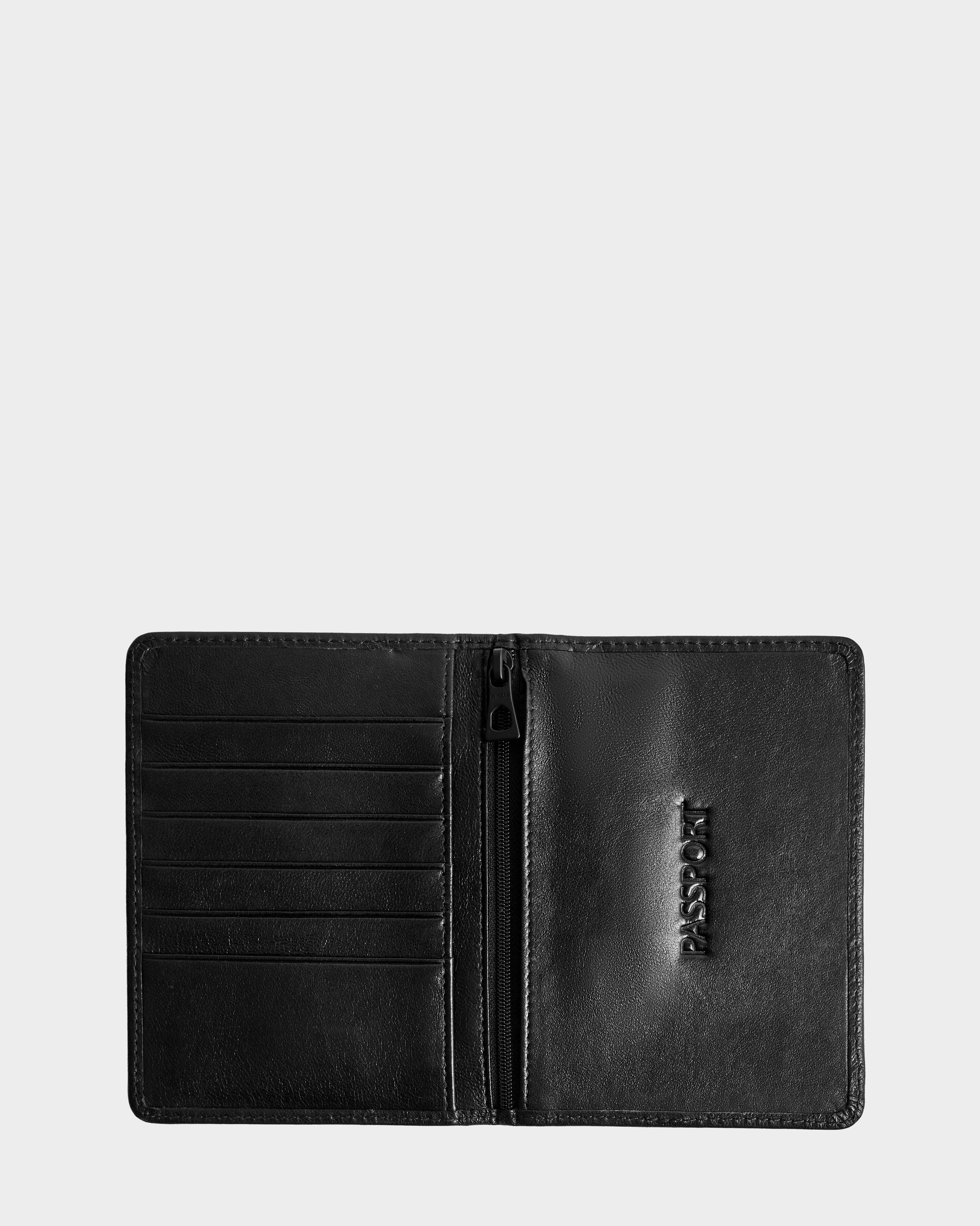 The Rudsak ROBIN - 9425562 Black passport holder is shown open, with card slots on the left, a center zip pocket, and PASSPORT embossed on the right side.